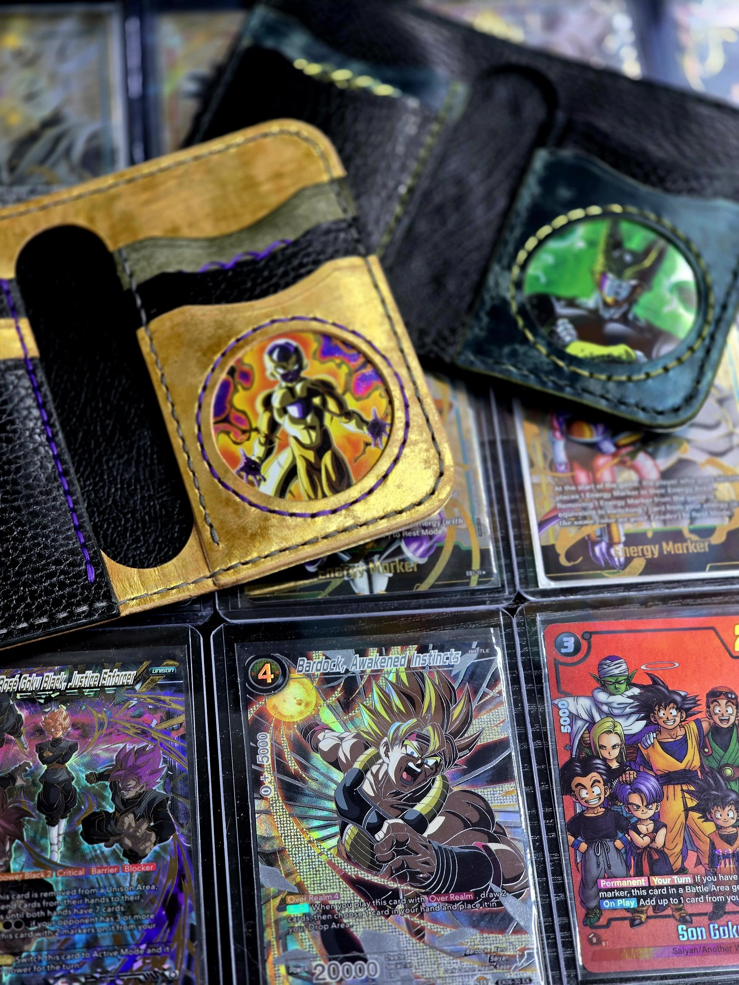 Close-up photo of Dragon Ball trading cards and a cardholder with an animated character on it, featuring multiple cards with colorful artwork from the Dragon Ball series.