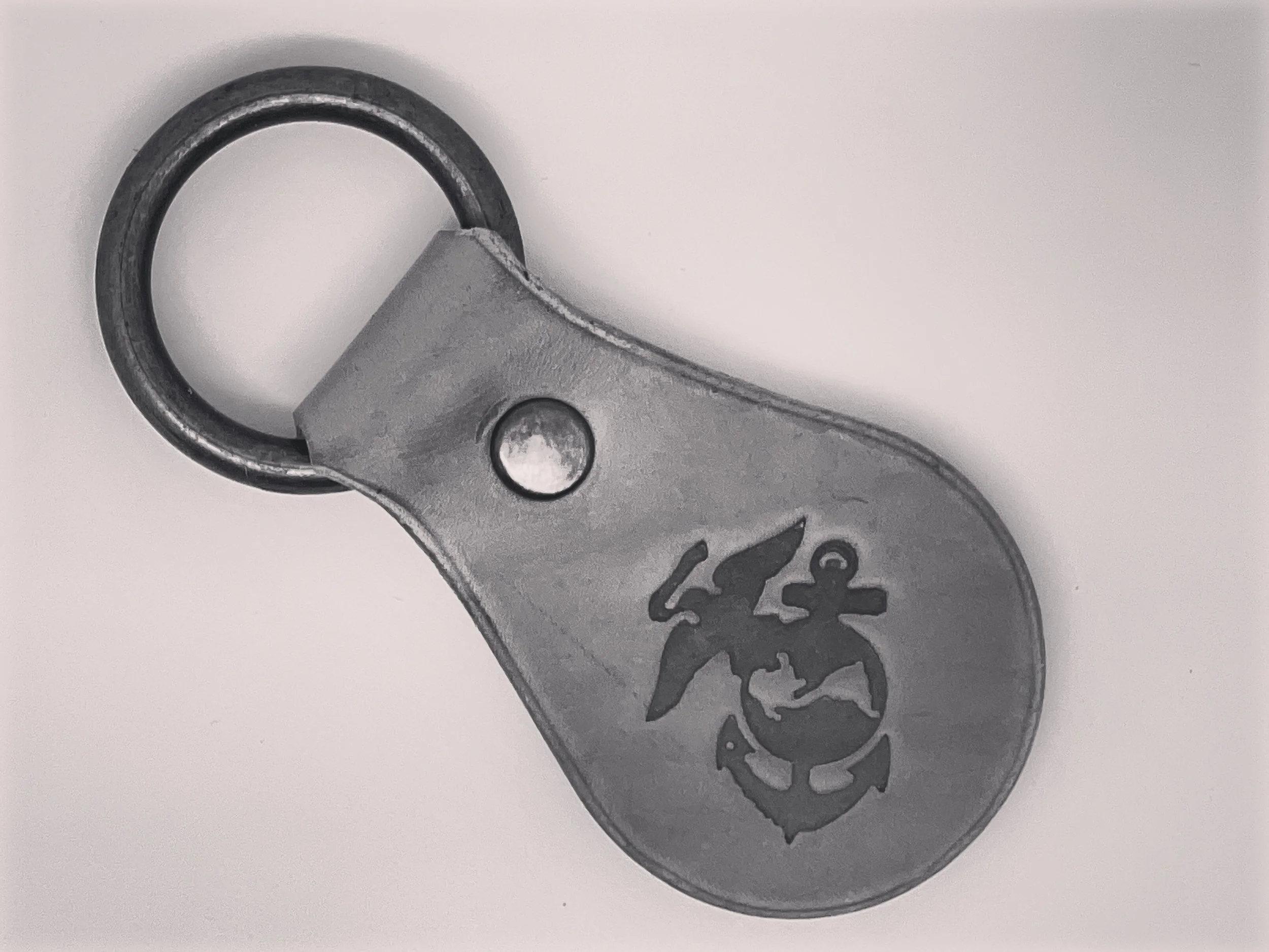 A silver metal Marine Corps keychain with an engraved Marine insignia and an oak leaf, attached to a black metal ring.
