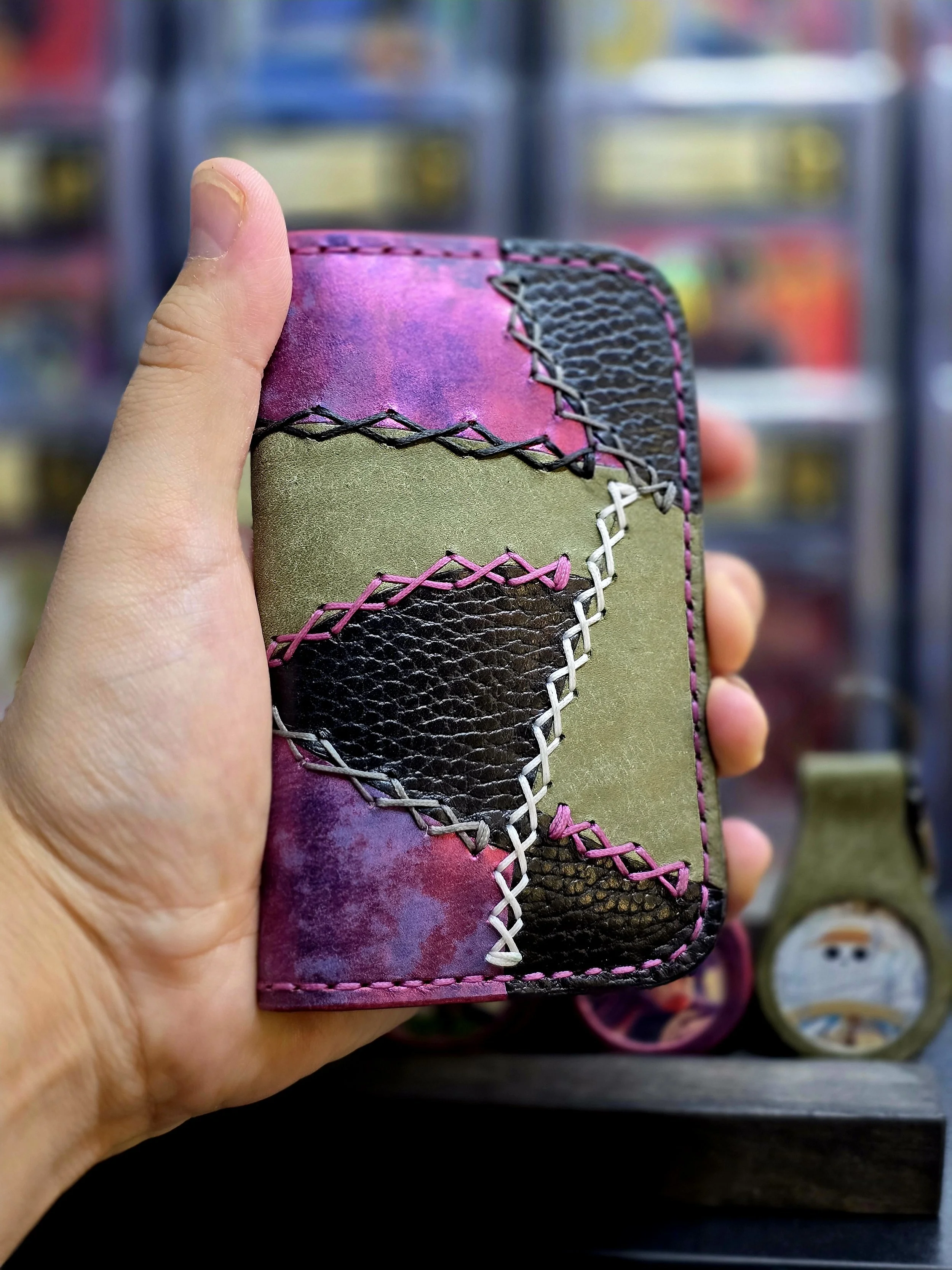 Hand holding a colorful patchwork leather wallet with stitching details.