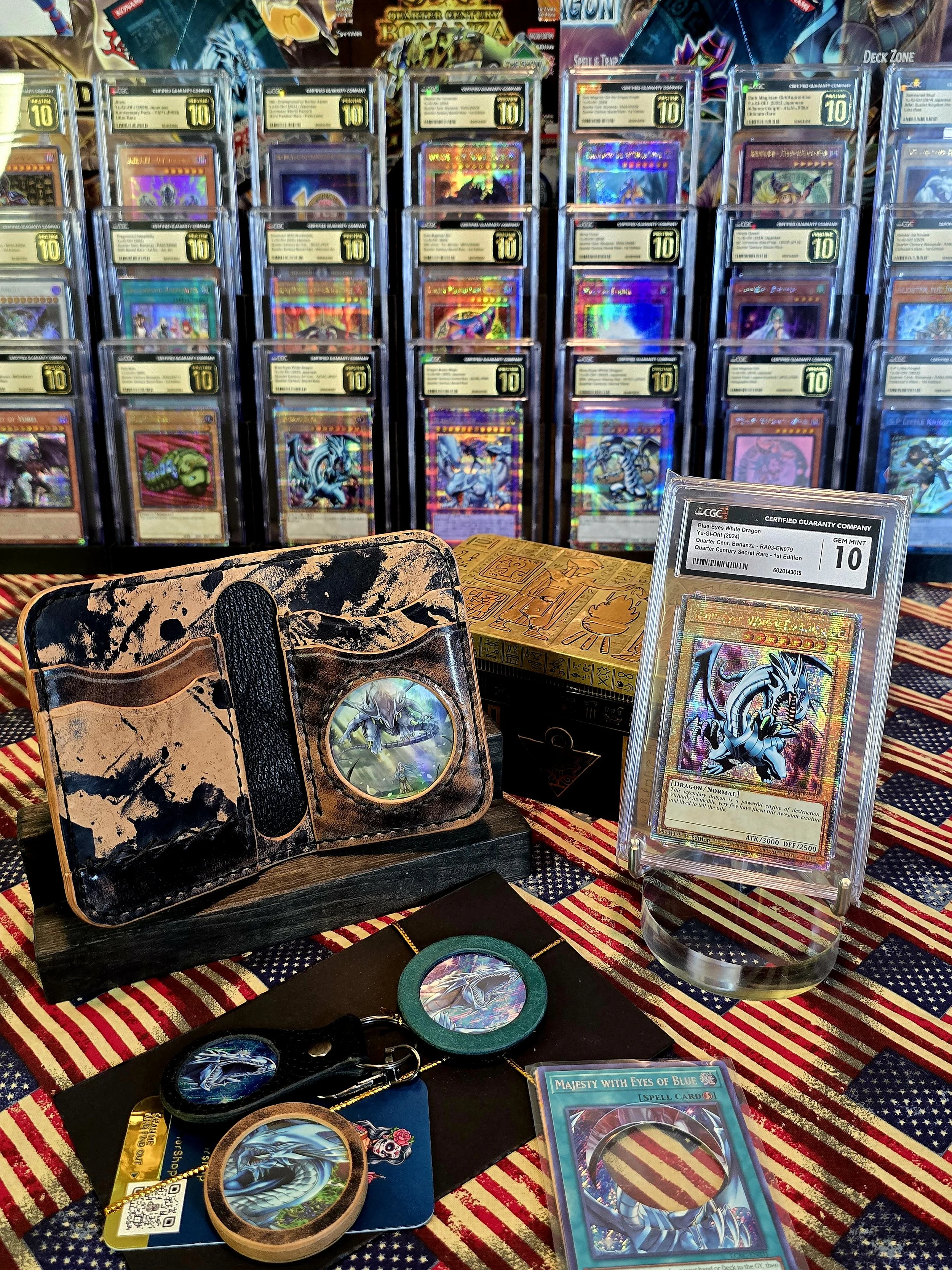 Display of collectible Yu-Gi-Oh! trading cards, including a heavily holographic card in a protective case, with several other cards and memorabilia arranged on a table with an American flag cloth. A vintage-style card holder with a dragon illustratio