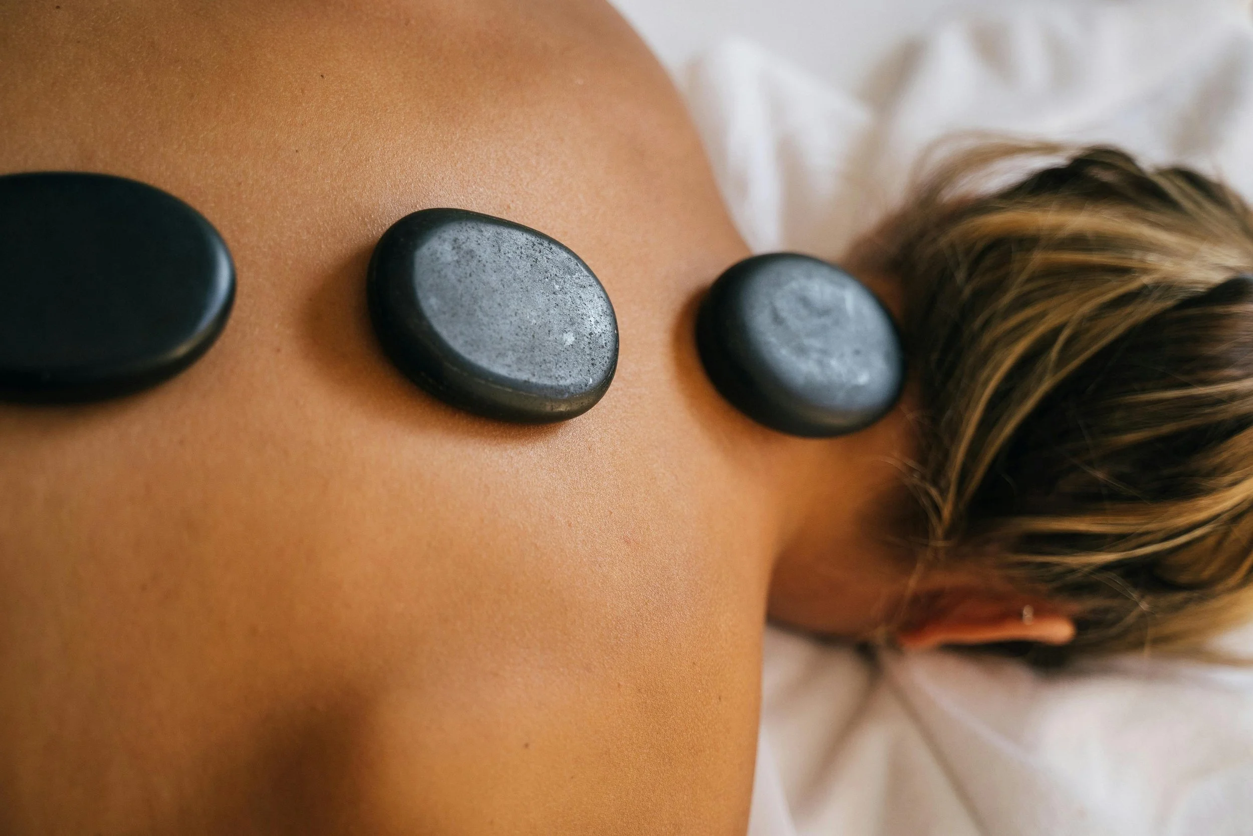 Hot-cold rock therapy massage performed by a licensed massage therapist in Lake Charles, Louisiana, using heated and cooled stones for muscle relief.