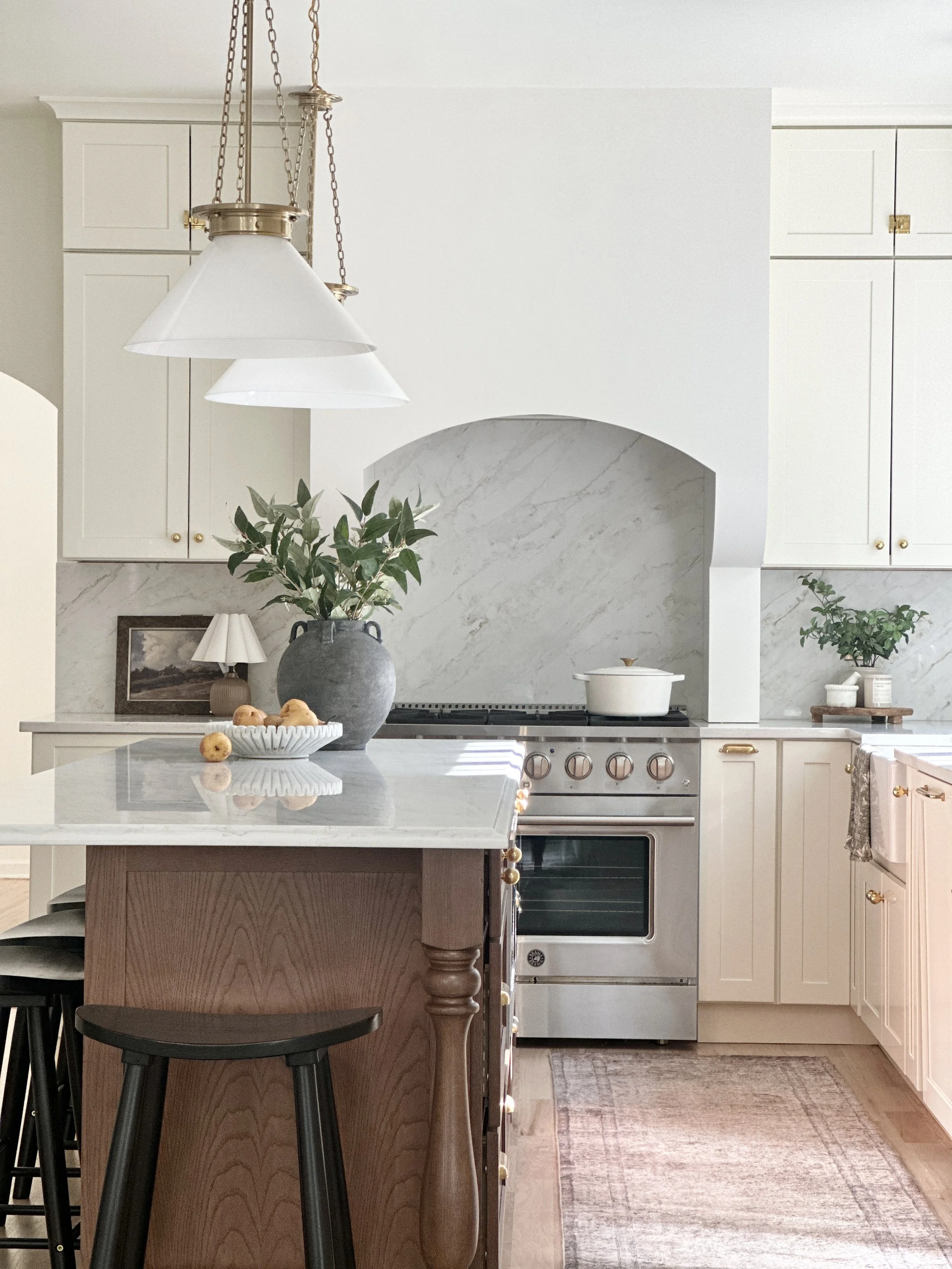 Neutral kitchen with arched marble range hood and wood island, designed by Lily & Nest Homes, Millstone NJ