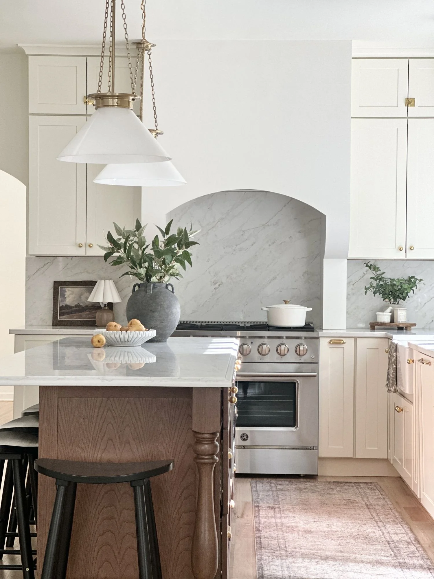 Warm white kitchen with an arched marble range hood and a white oak island | Lily & Nest Homes, New Jersey interior design