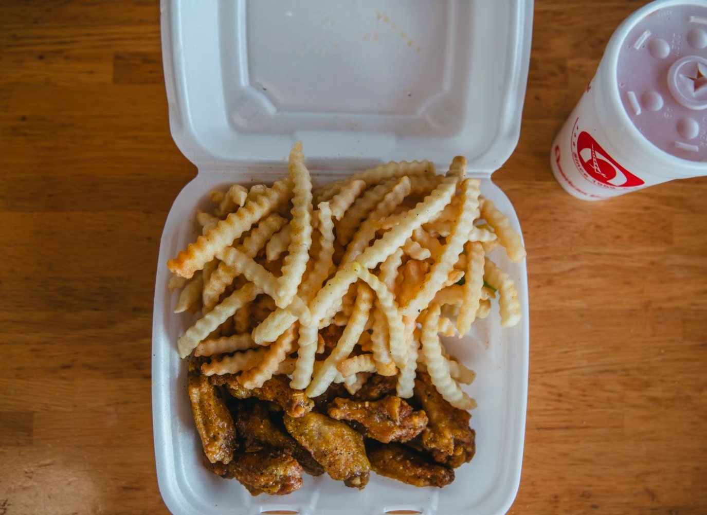 Photo of a foam take-out box with Lemon Pepper wings and fries.