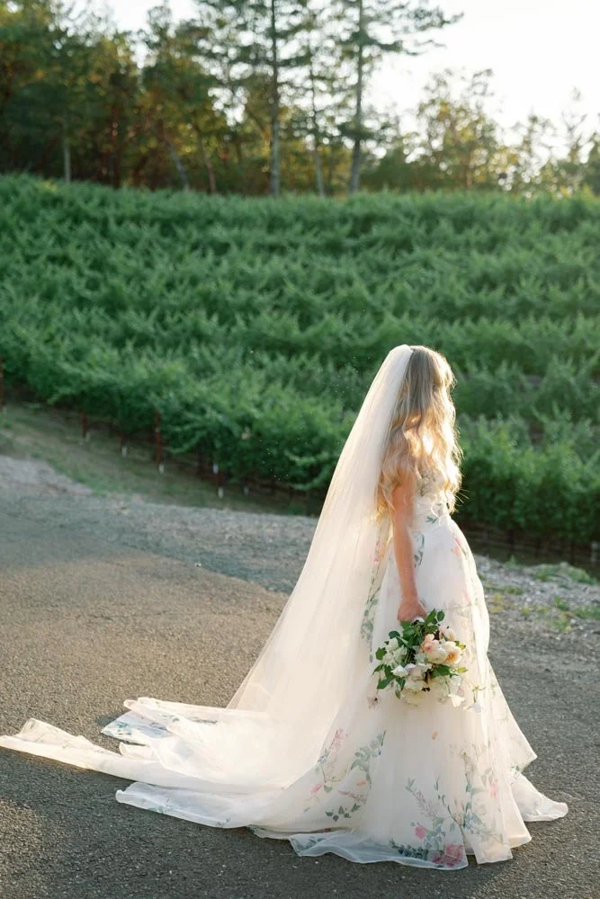 a bride looking away from the camera with a bouquet in her hand during a sunset wedding in napa california