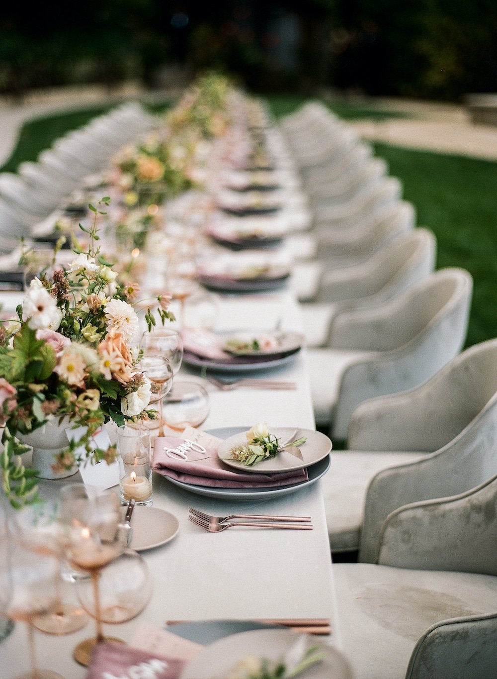 a table design in neatural tans and greys with pops of peach and pink accents in the table napkins and floral arrangement on the table