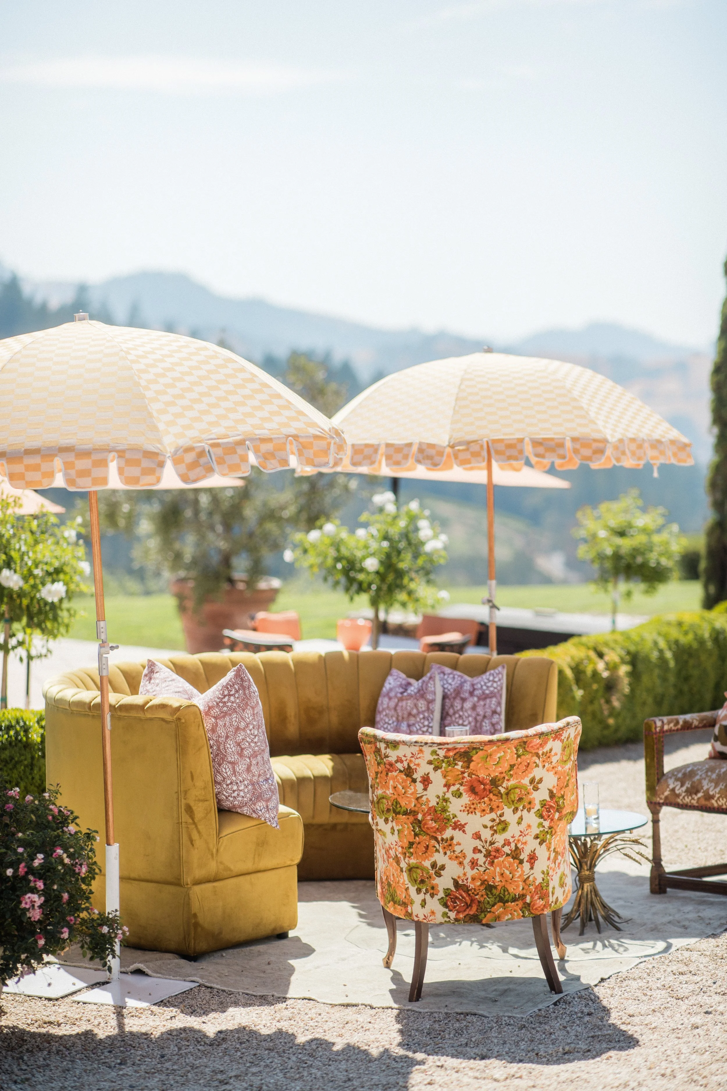 yellow and orange umbrellas shading a vintage looking arch chair and yellow couch on a patio at a sonoma wedding venue