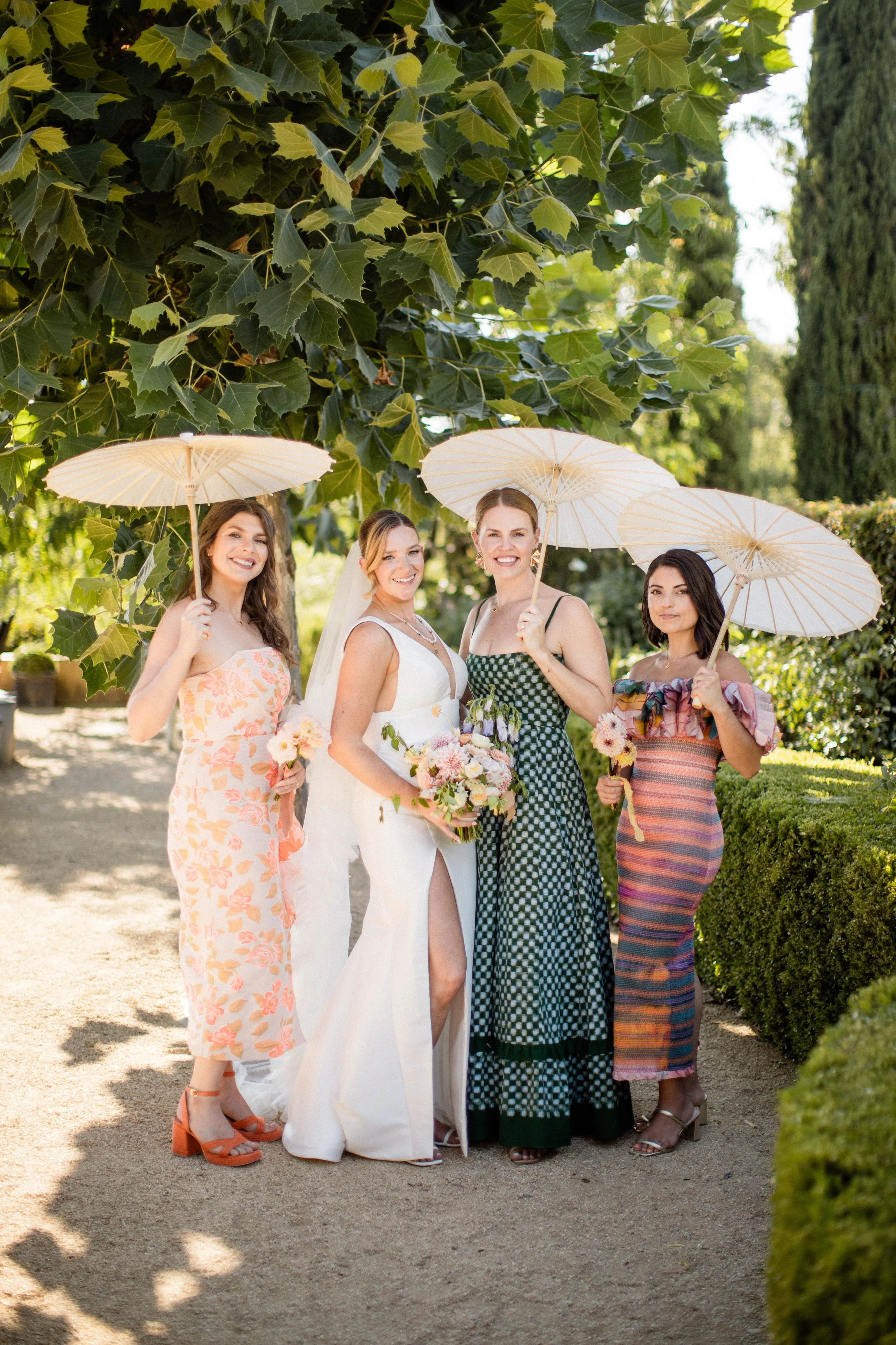 a bride and three bridesmaids standing near a tree and they're holding parasols for a sonoma wedding