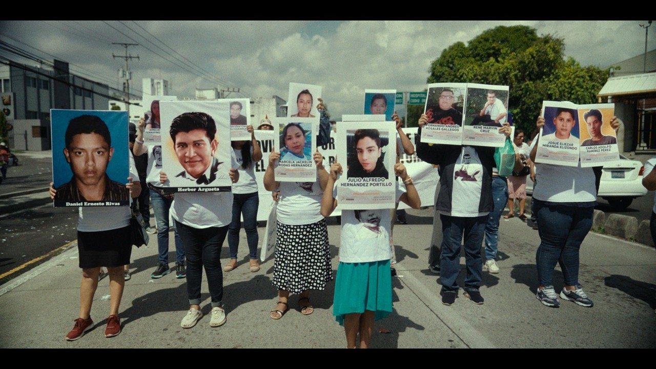 Group of protesters holding large photos of missing people during daylight