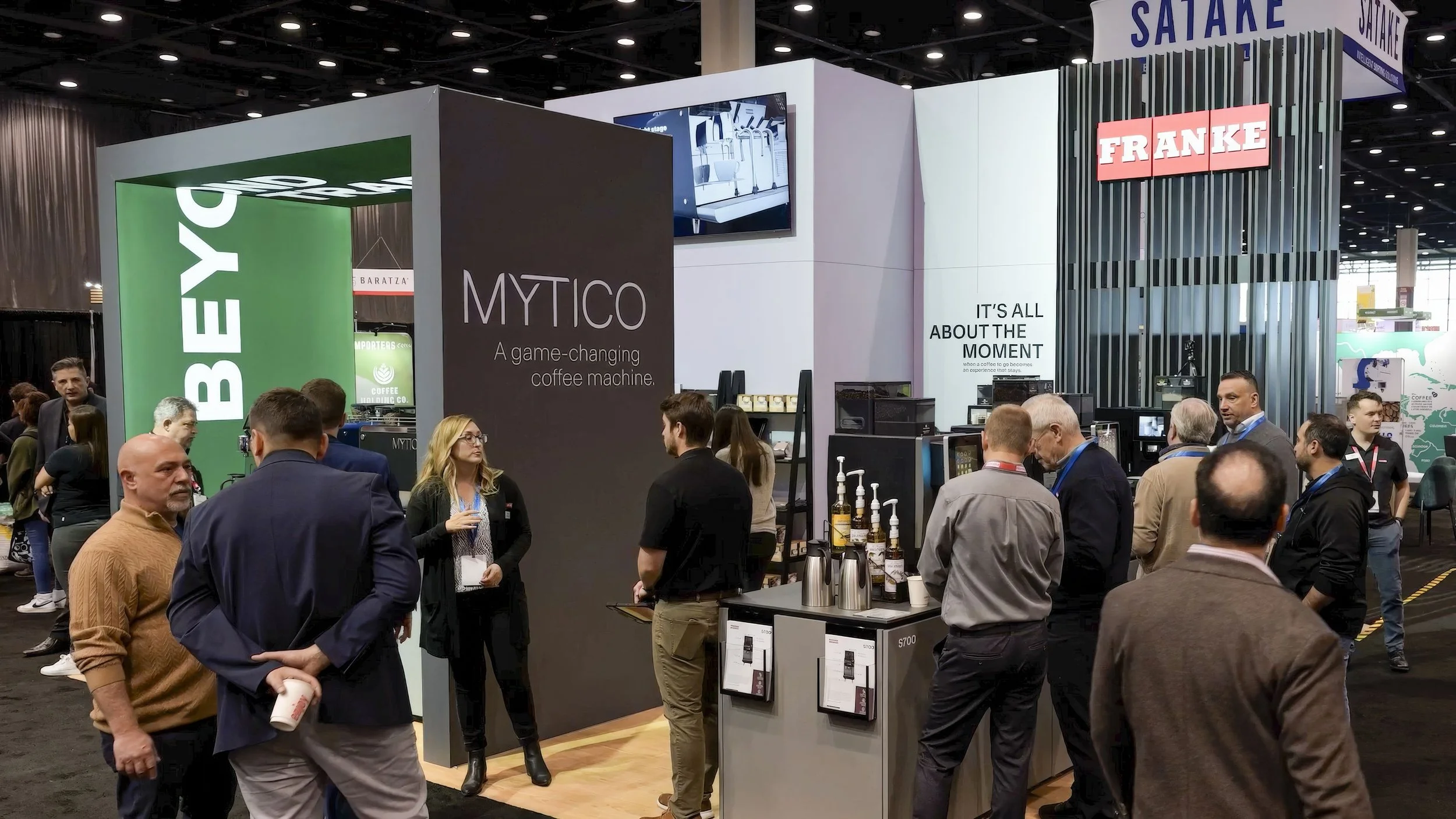 a busy modern trade show booth with signs and people