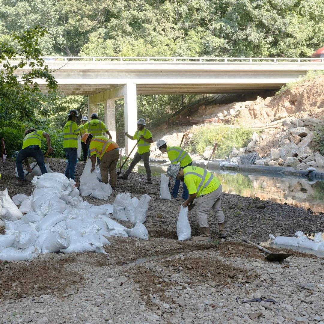 Men filling sandbags to protect a river.