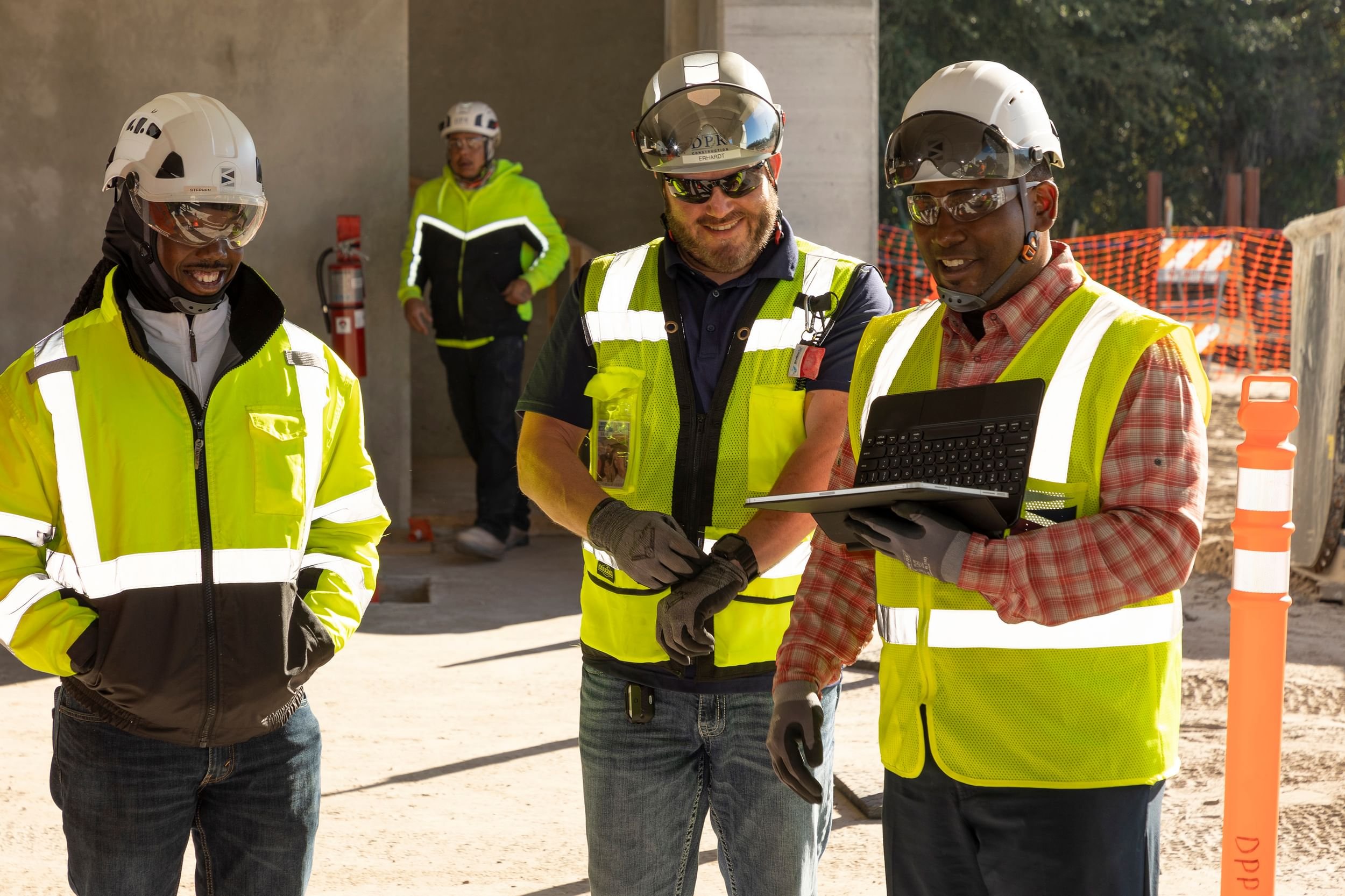 Team members review plans on a jobsite while wearing PPE