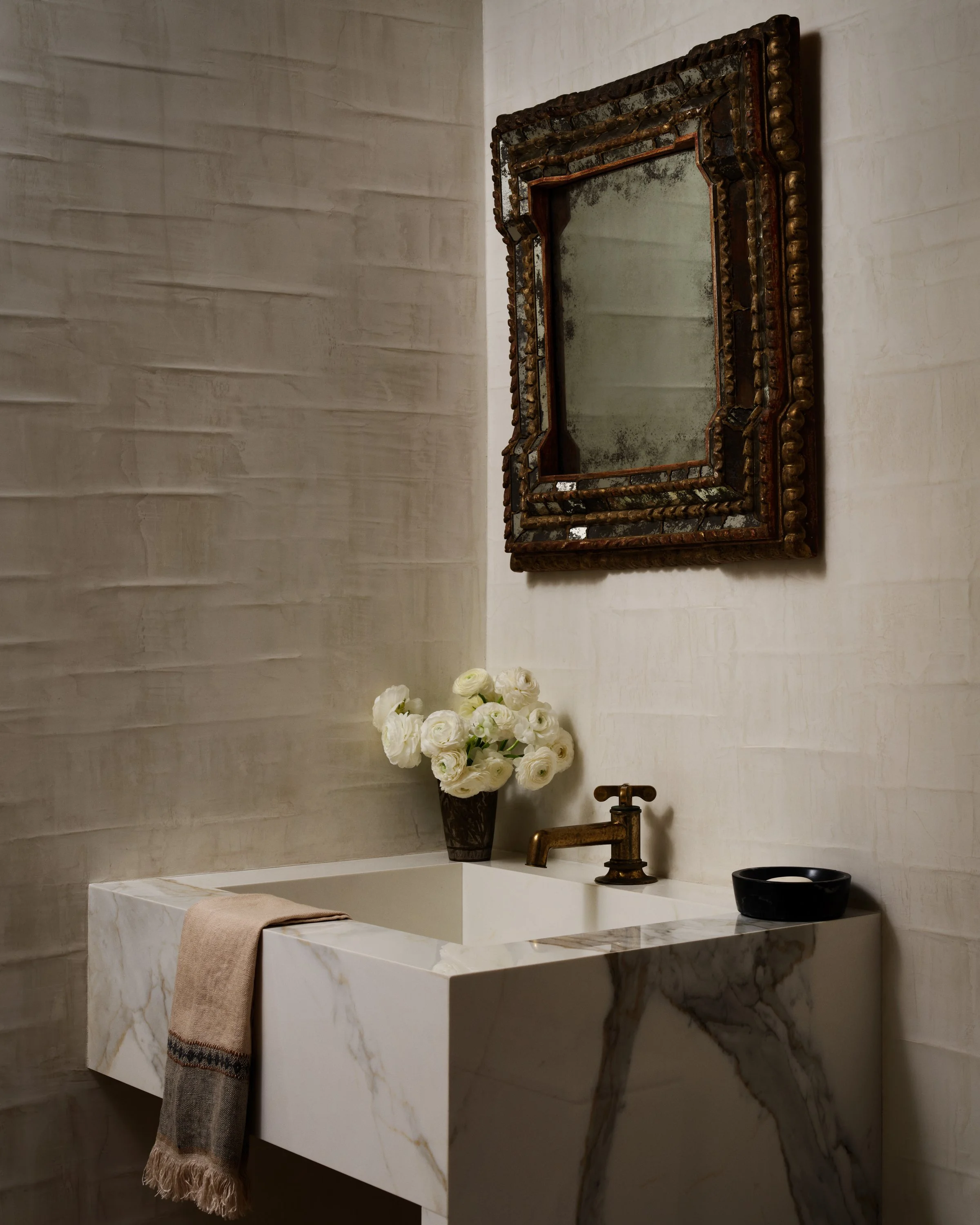 Powder room sink with decorative mirror and flowers.