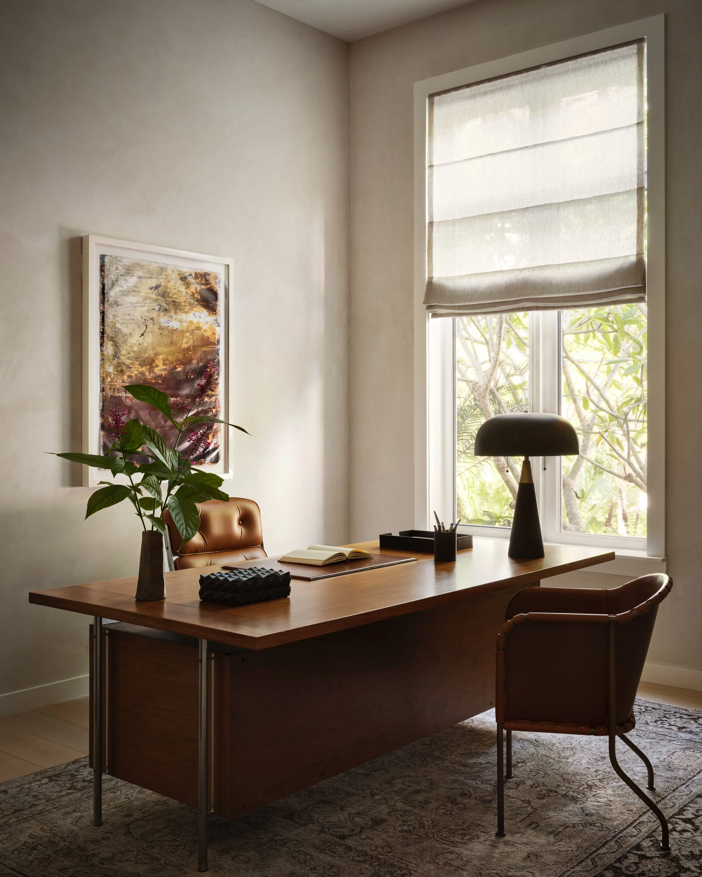 Desk with flowers, table lamp, two chairs.