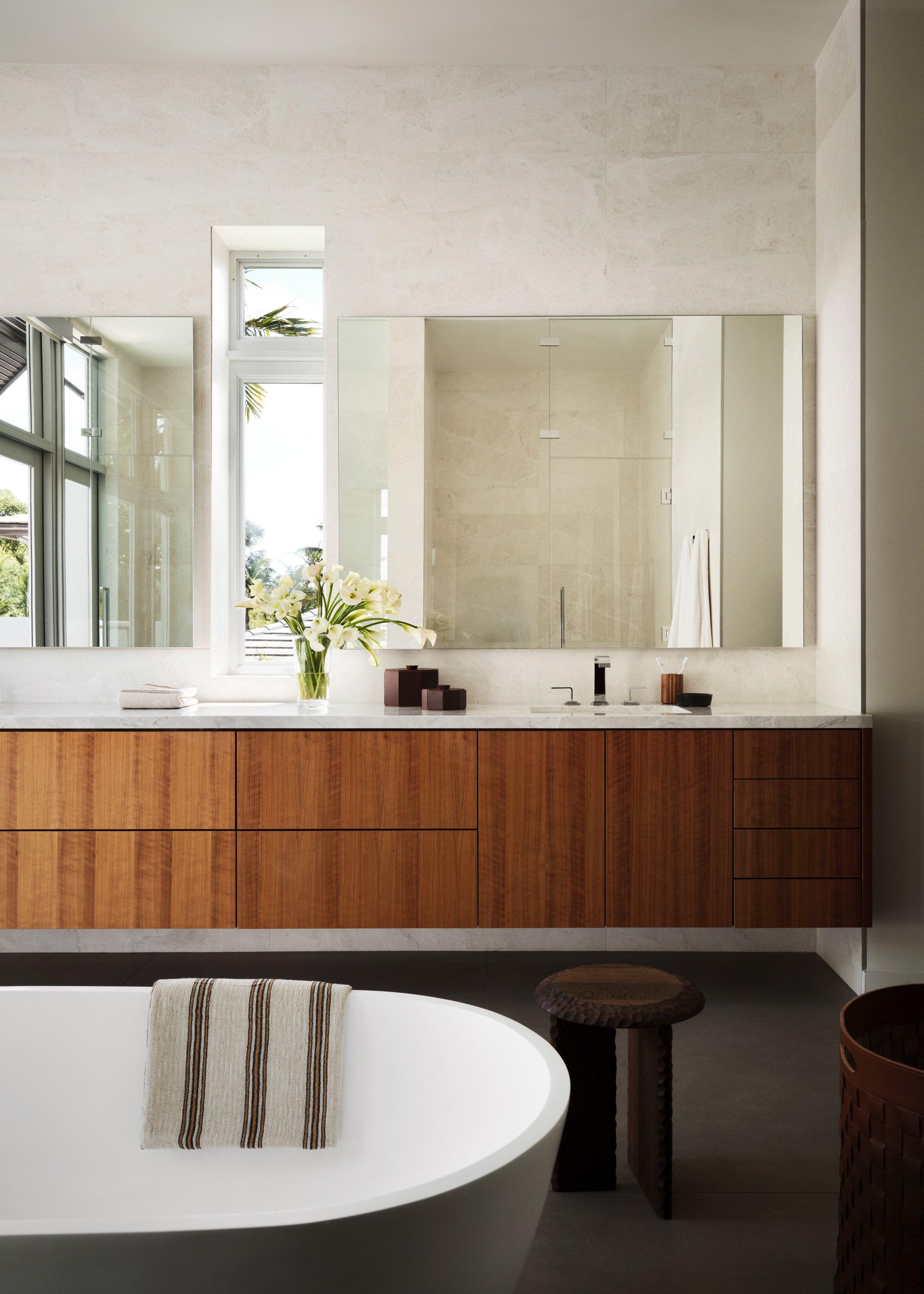 Bathroom view with tub, sink, mirrors and flowers.