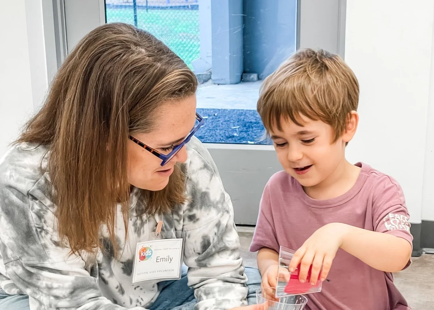 Restore Kids volunteer helping a child with an activity at Restore Houston Church