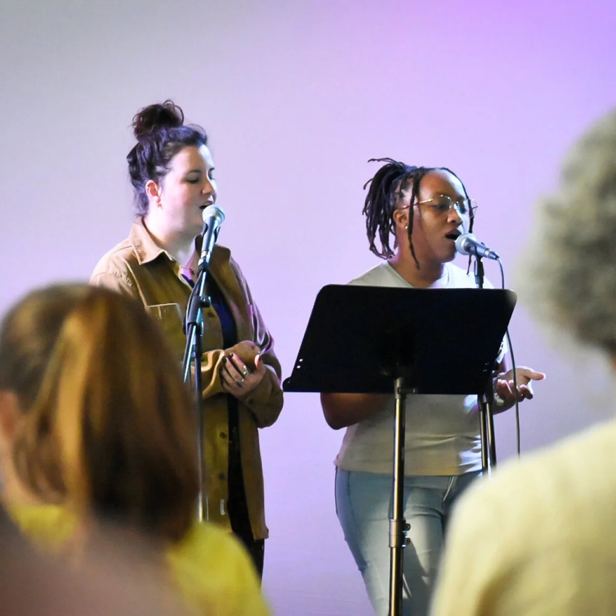 Two women singing during worship at Restore Houston Church