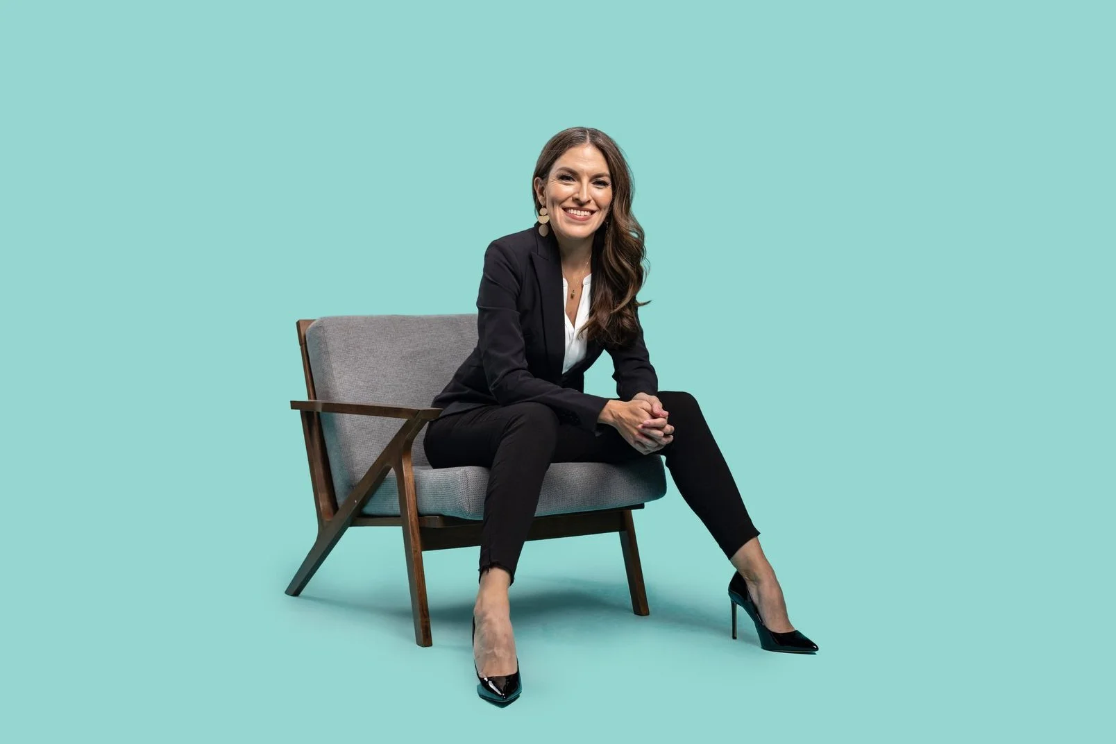 La abogada de inmigración Claudia P. López, sentada y sonriendo, con traje negro