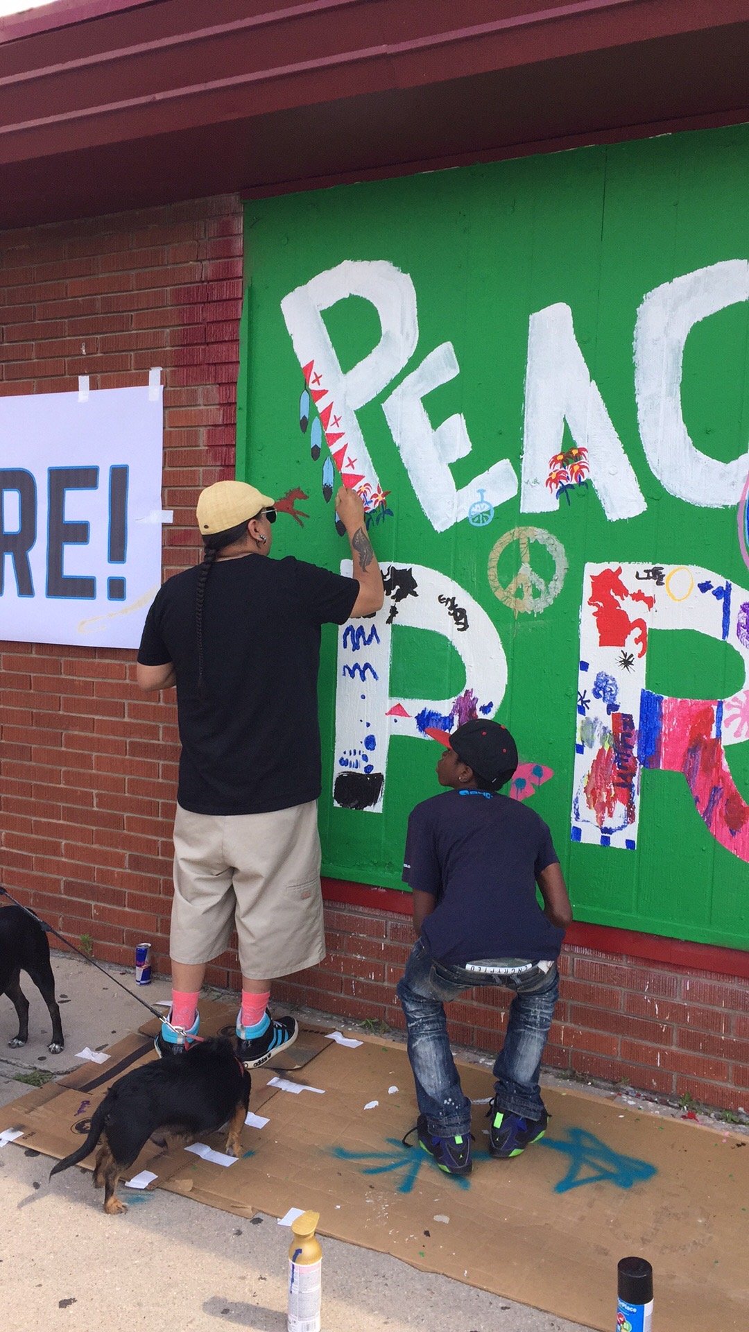 Neighbors participated in the weekend mural painting event. Free and open to the public, music, dancing, food, beverages, paint and tools were provided. Seen here: one community participant discusses his painting ideas with a younger participant.