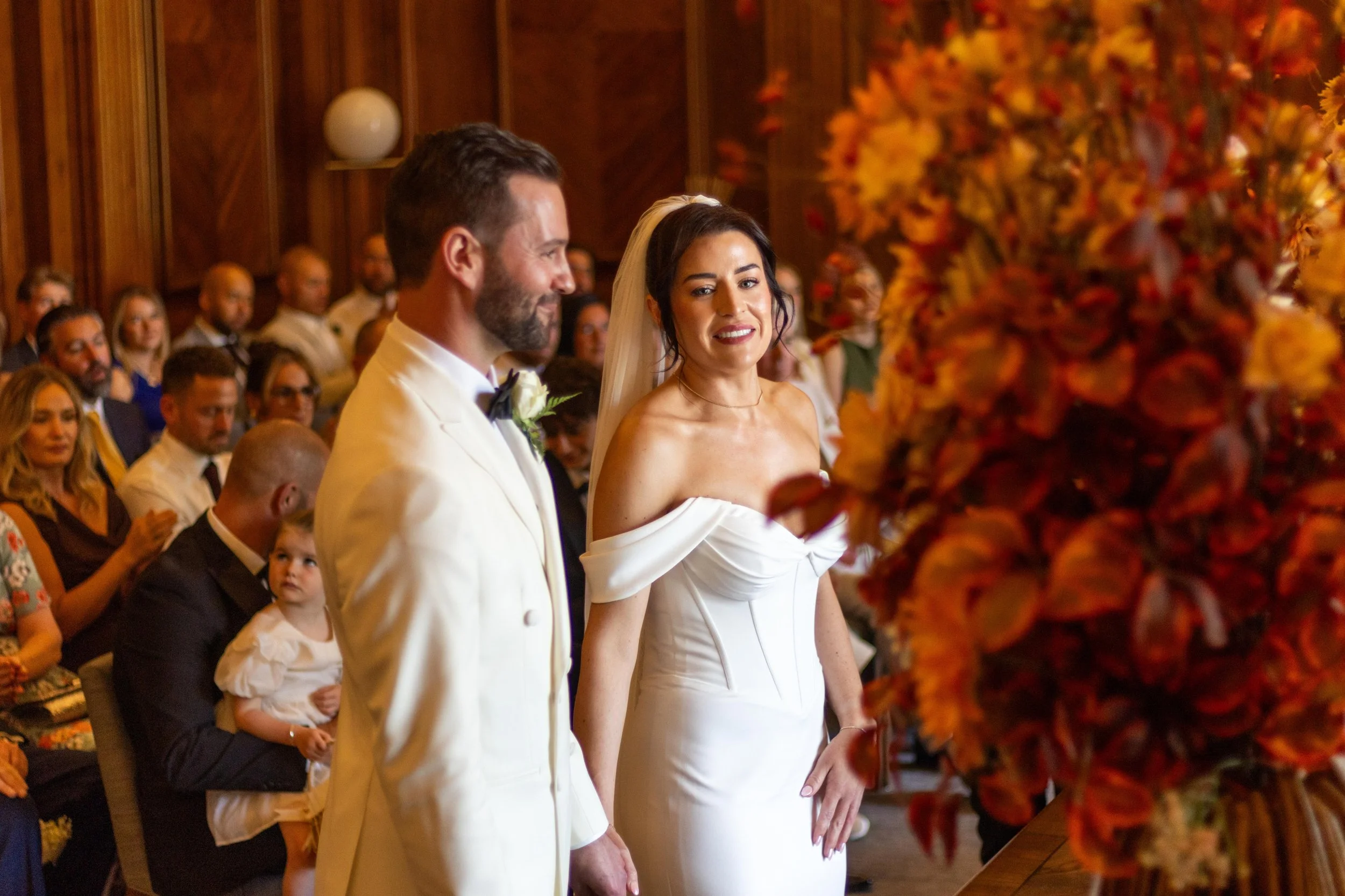 A bride and groom exchanging vows during their wedding ceremony in a decorated hall with guests watching.