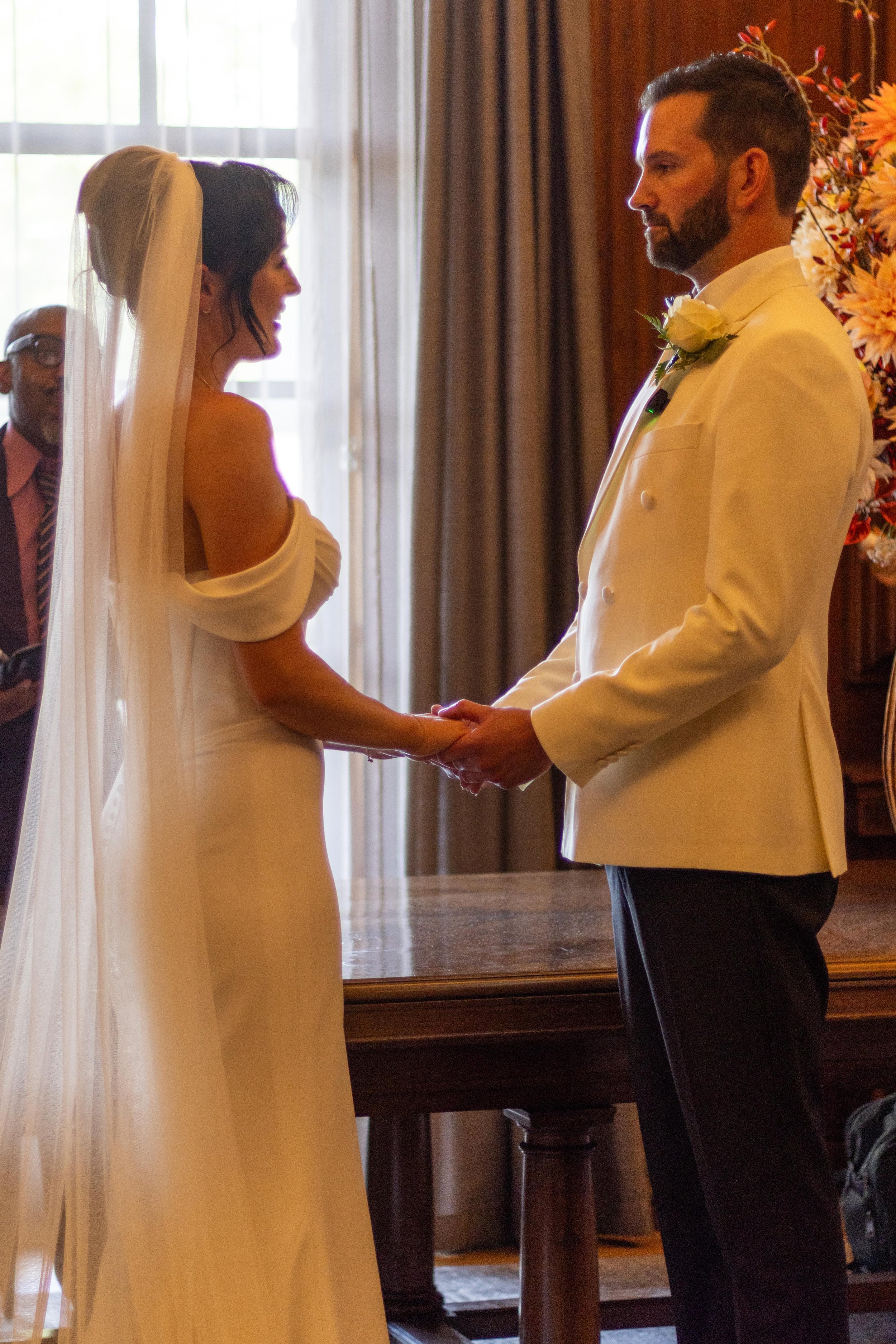A bride and groom holding hands during their wedding ceremony indoors.