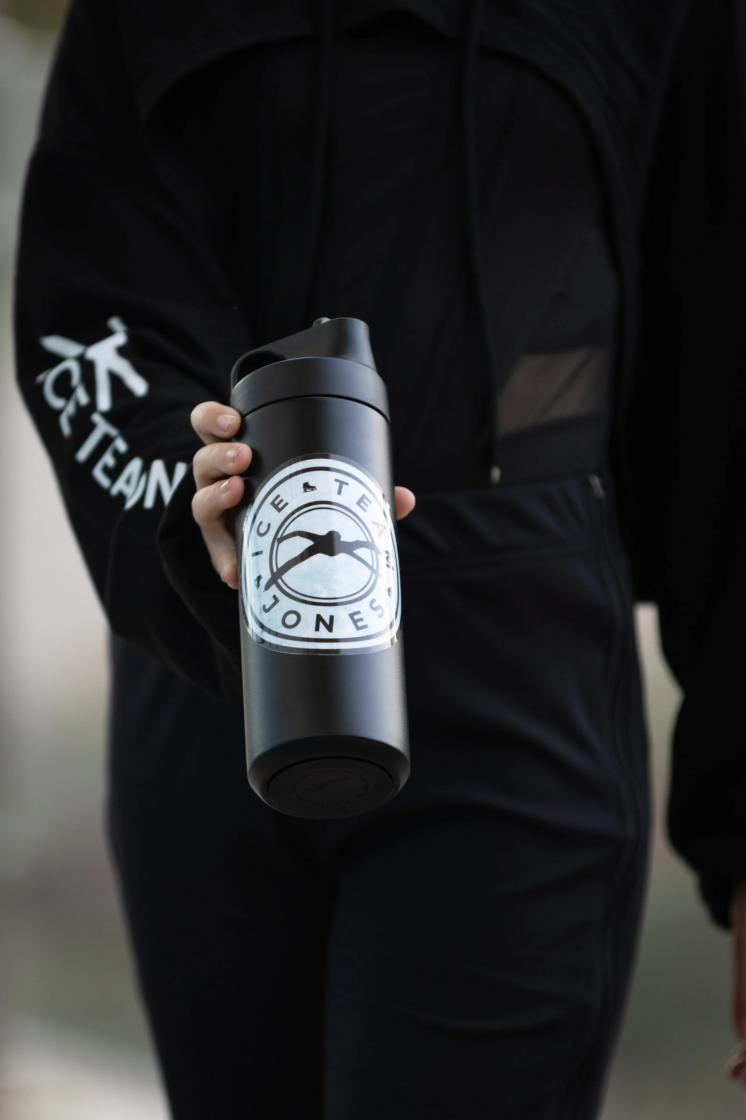 Person holding a black water bottle with a 'JONES' and mountain logo