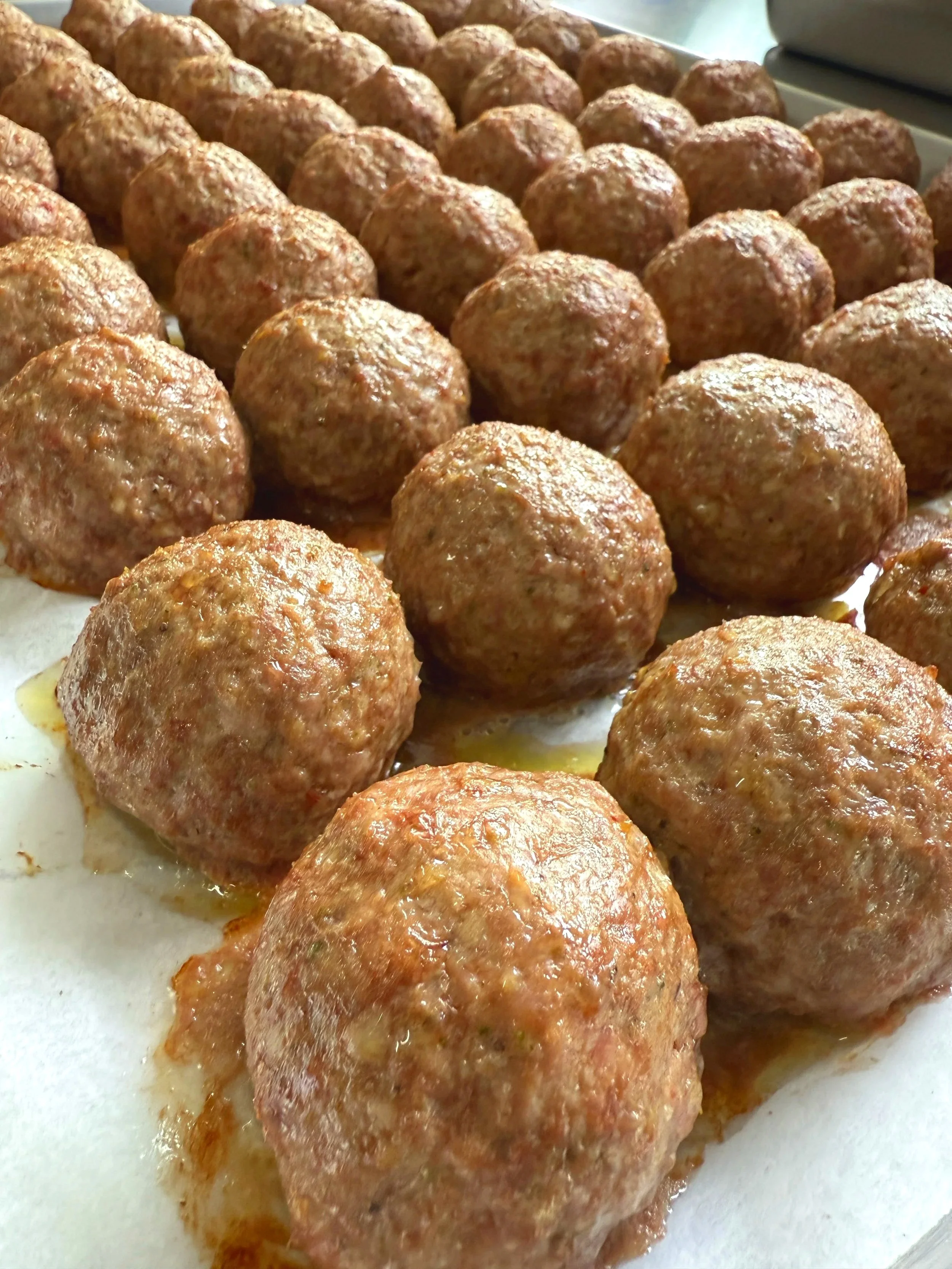 Close-up of cooked meatballs arranged on a baking sheet.