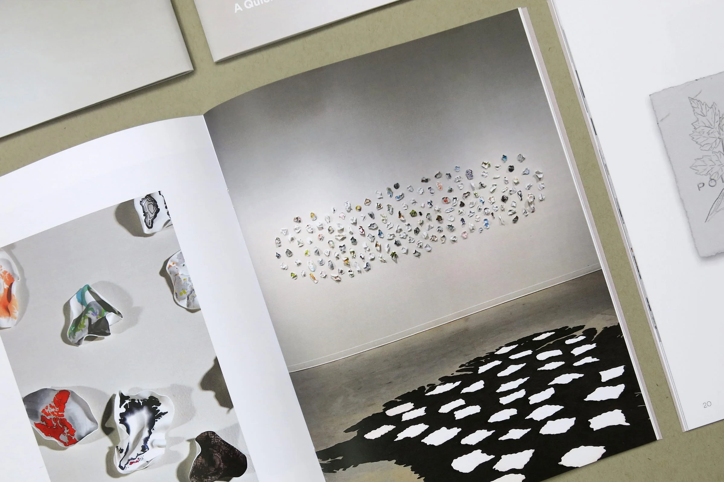 Details of book with artworks of sculptures on the walls and floor of a gallery.