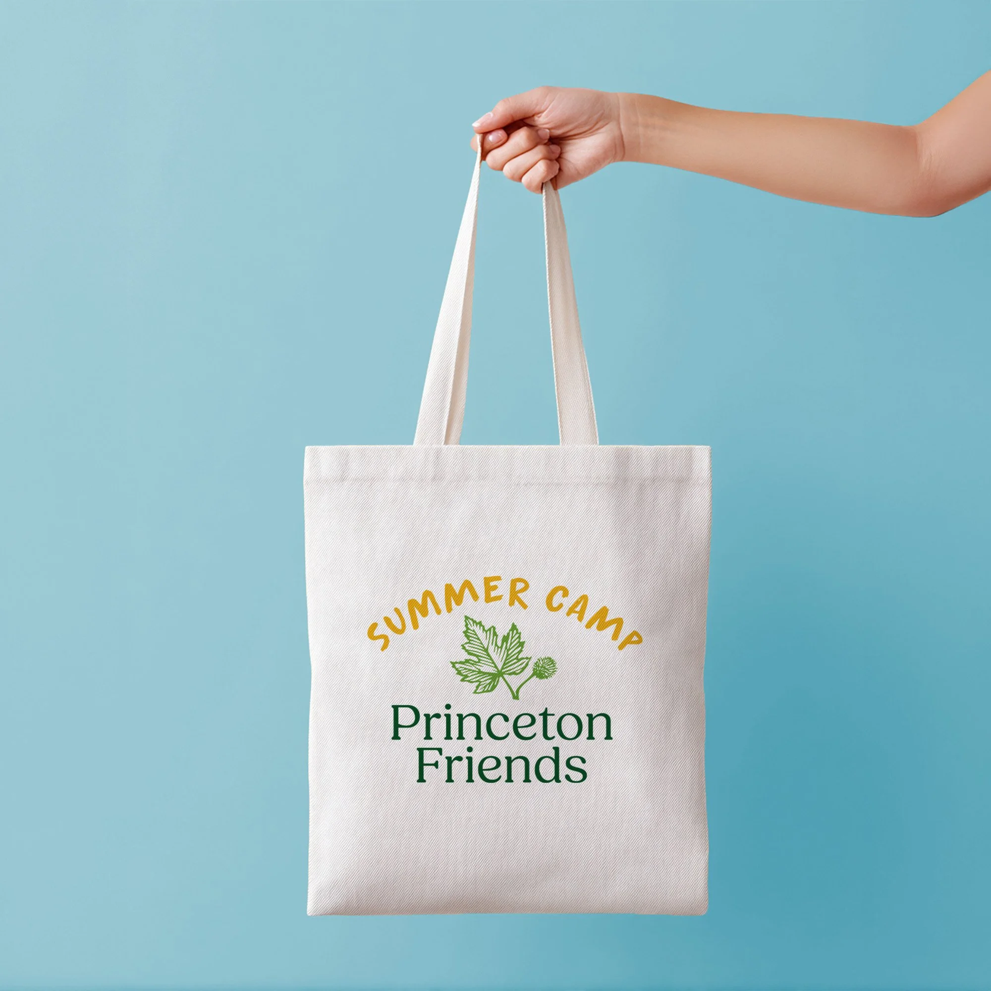 Tote bag with Princeton Friends School Summer camp logo. Extended hand holds bag.