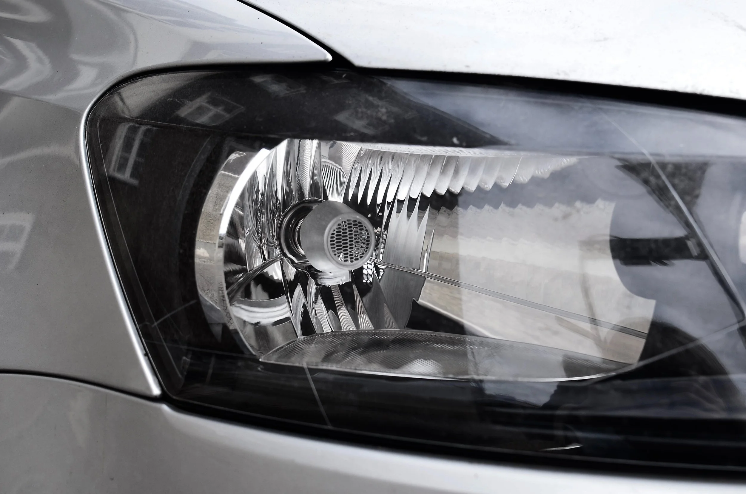 Close-up of a modern car's headlight with reflective inner components and clear outer lens.