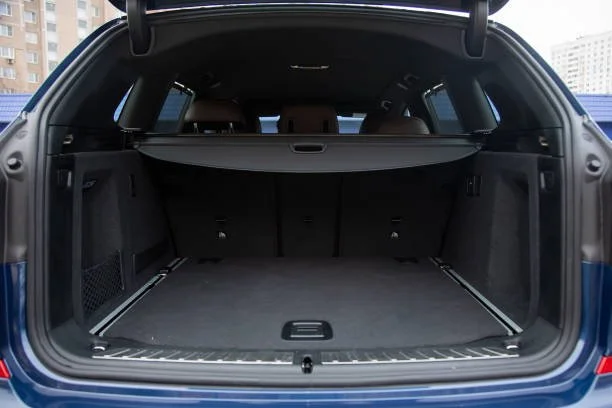 The trunk of a blue SUV with the rear hatch open, showing a spacious cargo area with black interior and a retractable cargo cover.