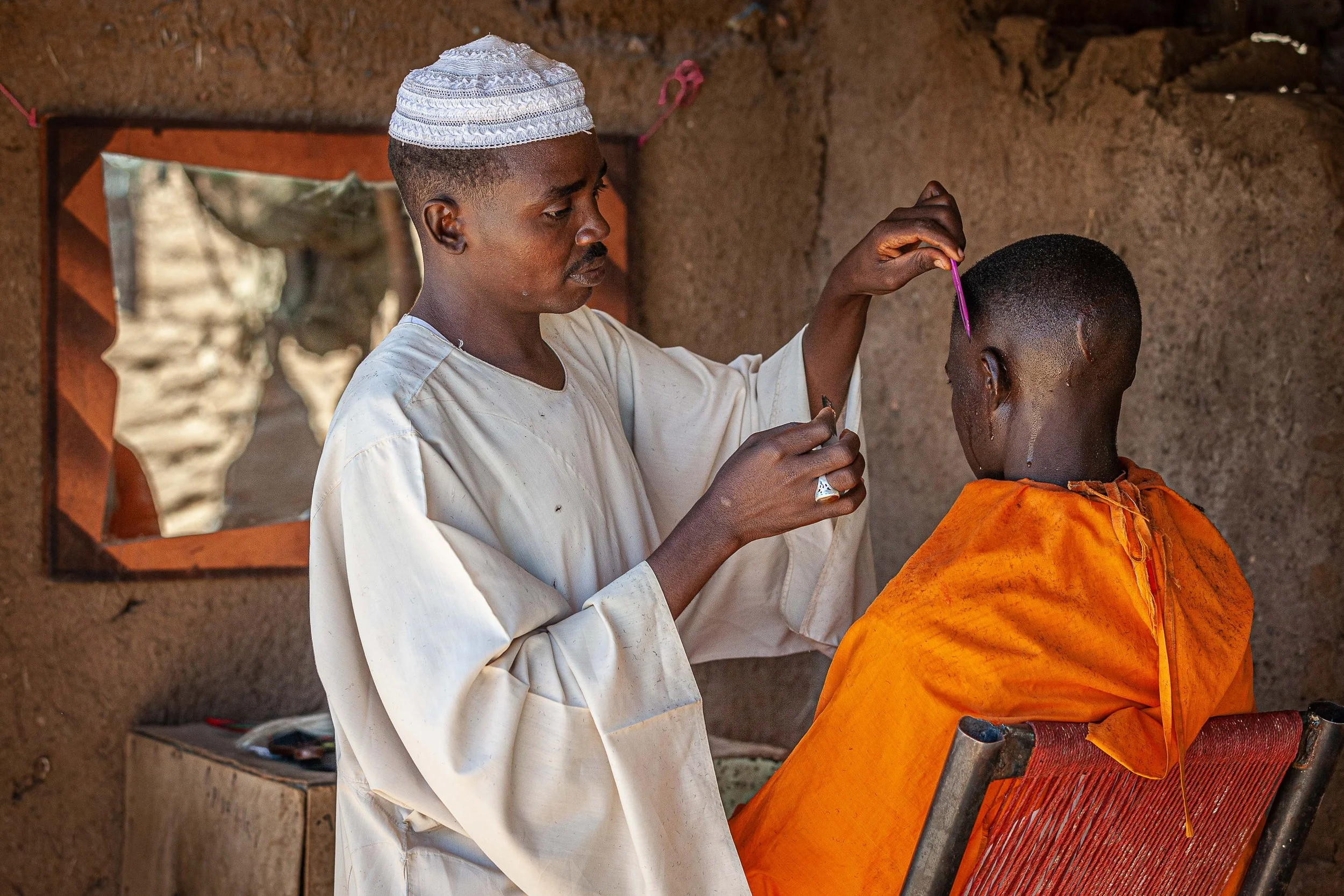 Zam Zam IDP Camp, El Fasher, Darfur, Sudan — a barber gives a resident a haircut. Small businesses like this reflect the resilience of displaced communities and provide essential services needed to sustain residents of the camp.
Camp de déplacés de Z