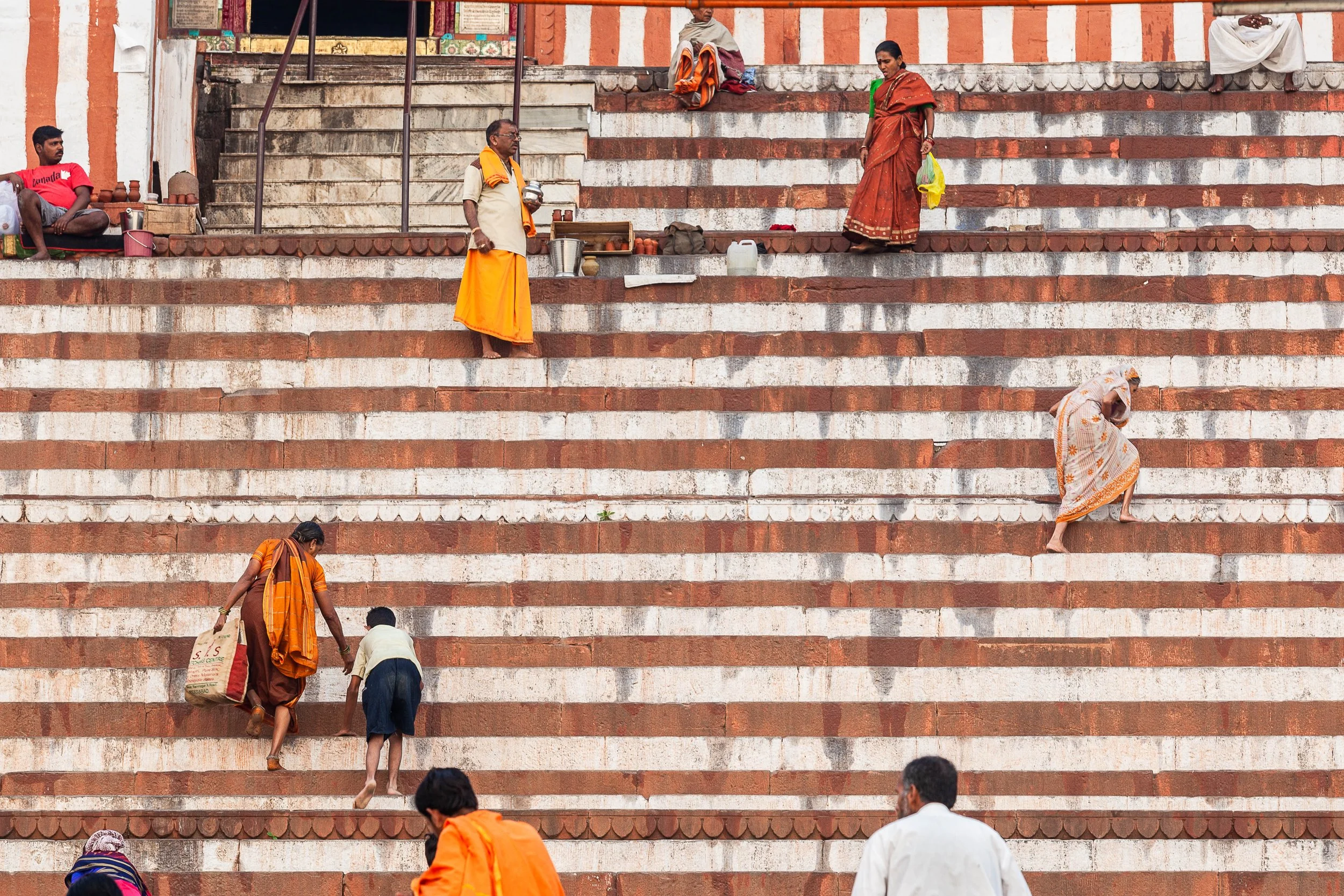Varanasi, India — people climb the worn steps of the ghats, where spiritual life and daily rhythms meet along the Ganges.
Varanasi, Inde — des personnes gravissent les marches usées des ghats, où se rencontrent vie spirituelle et quotidien le long du