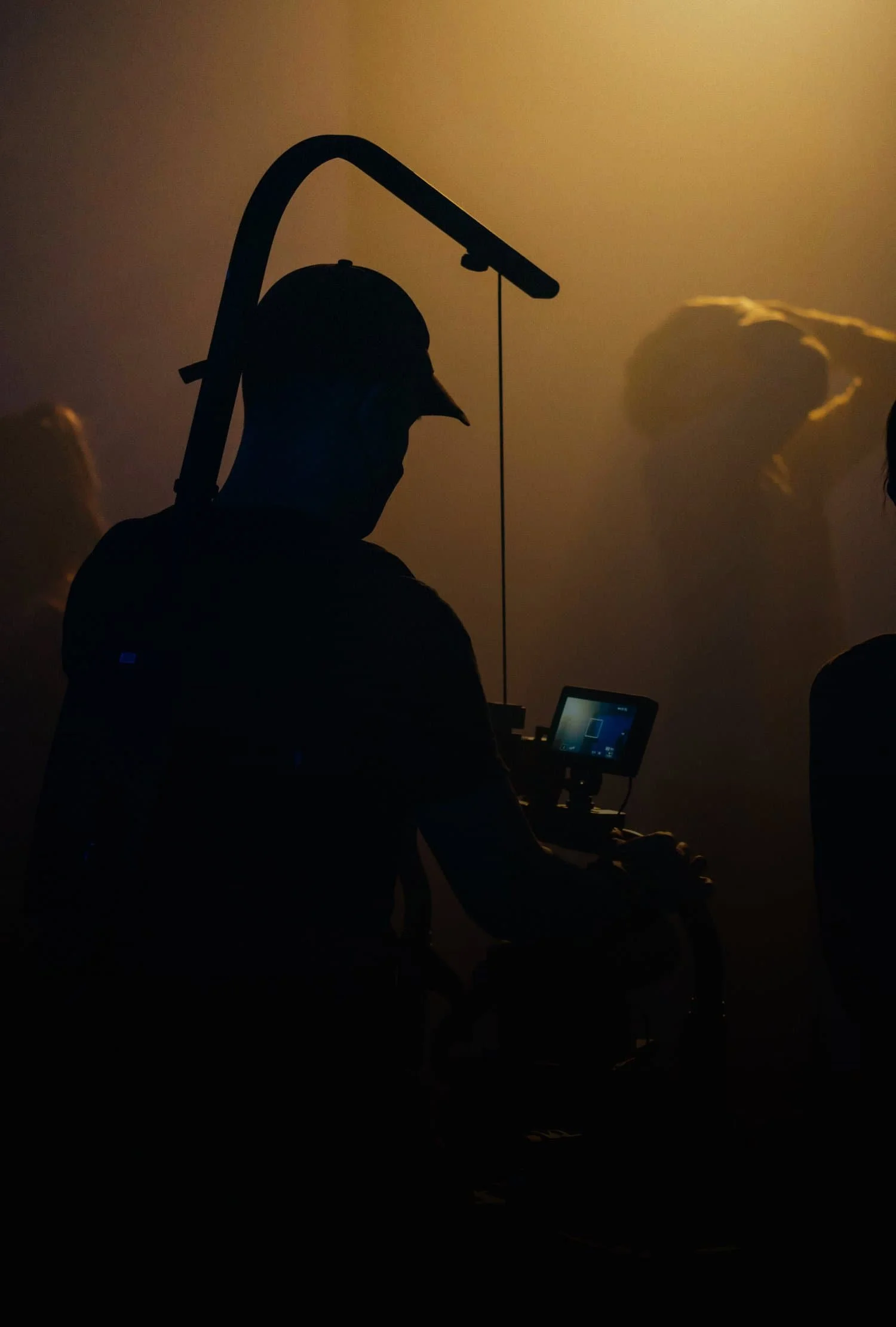 Silhouette d'un vidéaste professionnel opérant une caméra de cinéma dans un studio de tournage éclairé.