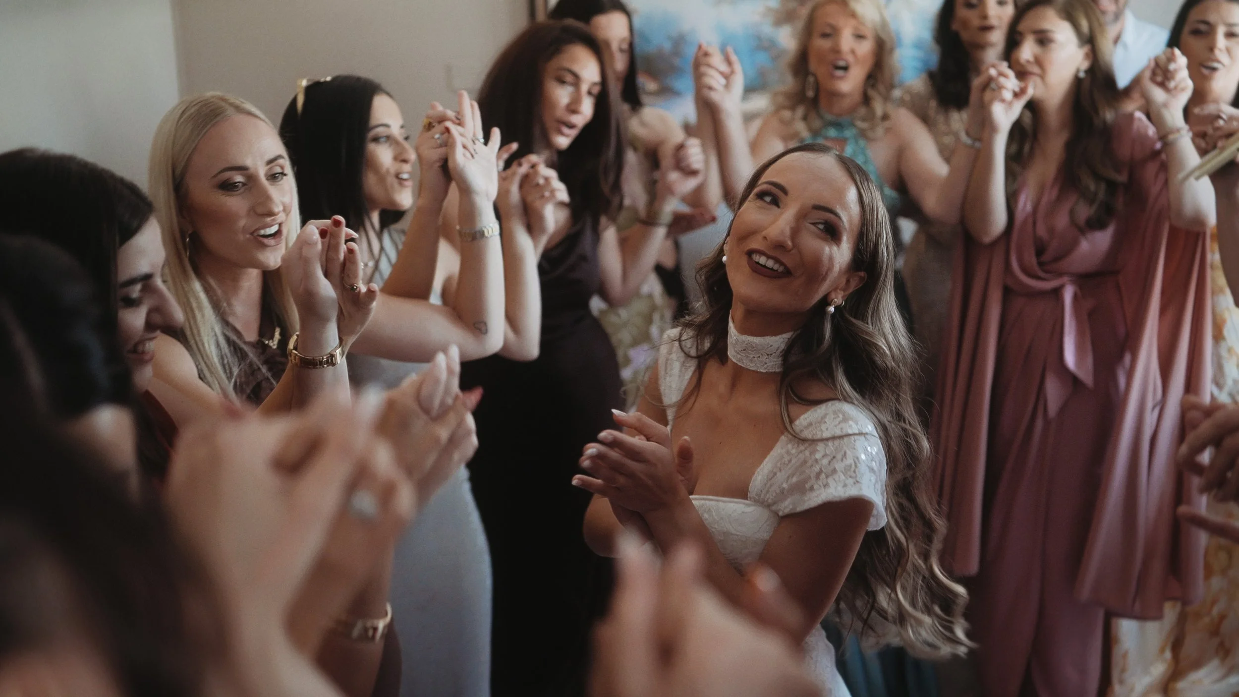 Bride smiling surrounded by friends clapping during traditional Cypriot bridal preparation, Agios Athanasios Cyprus, Red Lens Films