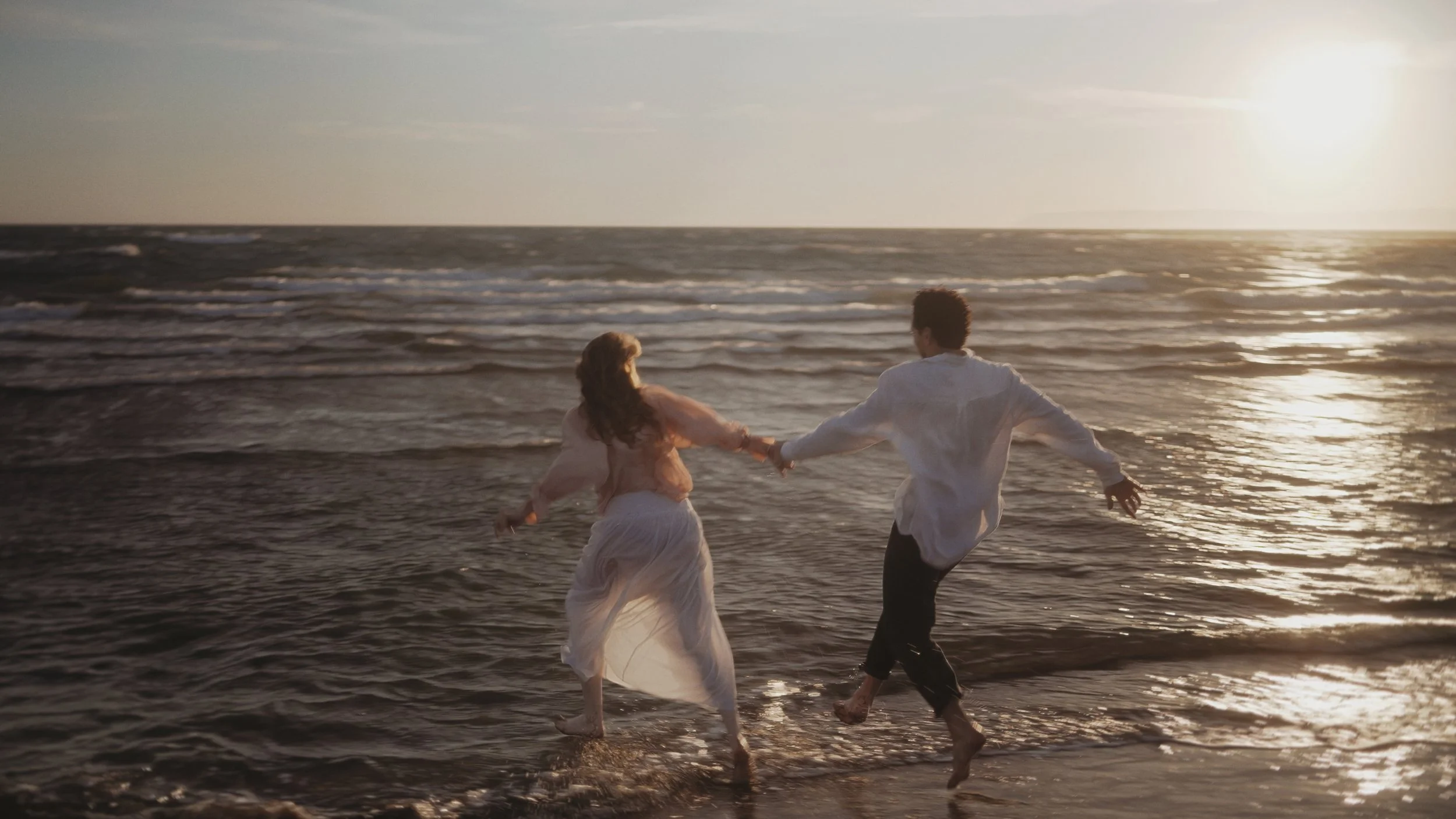Couple running hand in hand through the sea at sunset, Akrotiri beach, Cyprus, Red Lens Films