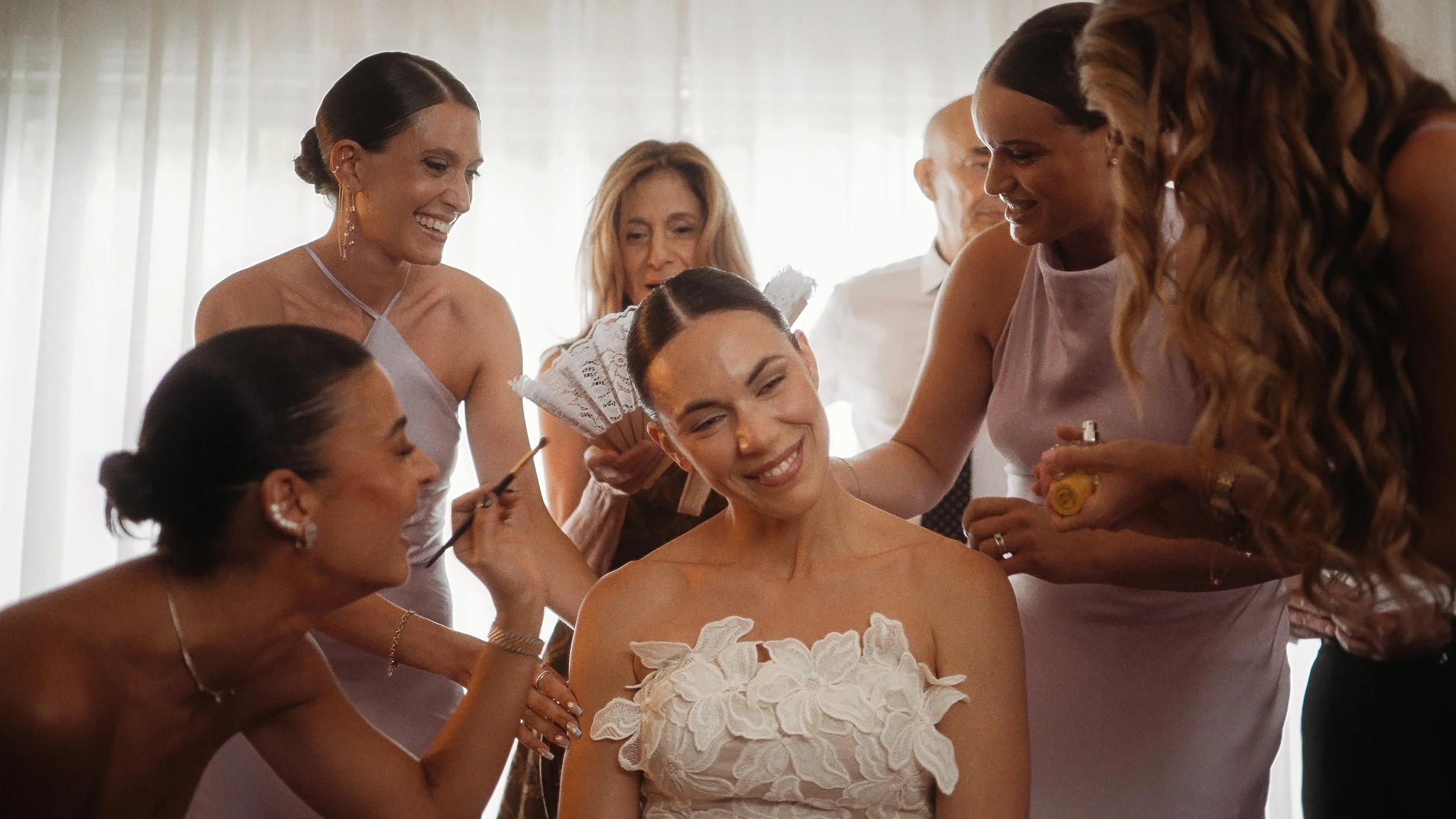 Bride smiling surrounded by bridesmaids and family during wedding morning preparations, Nicosia Cyprus, Red Lens Films
