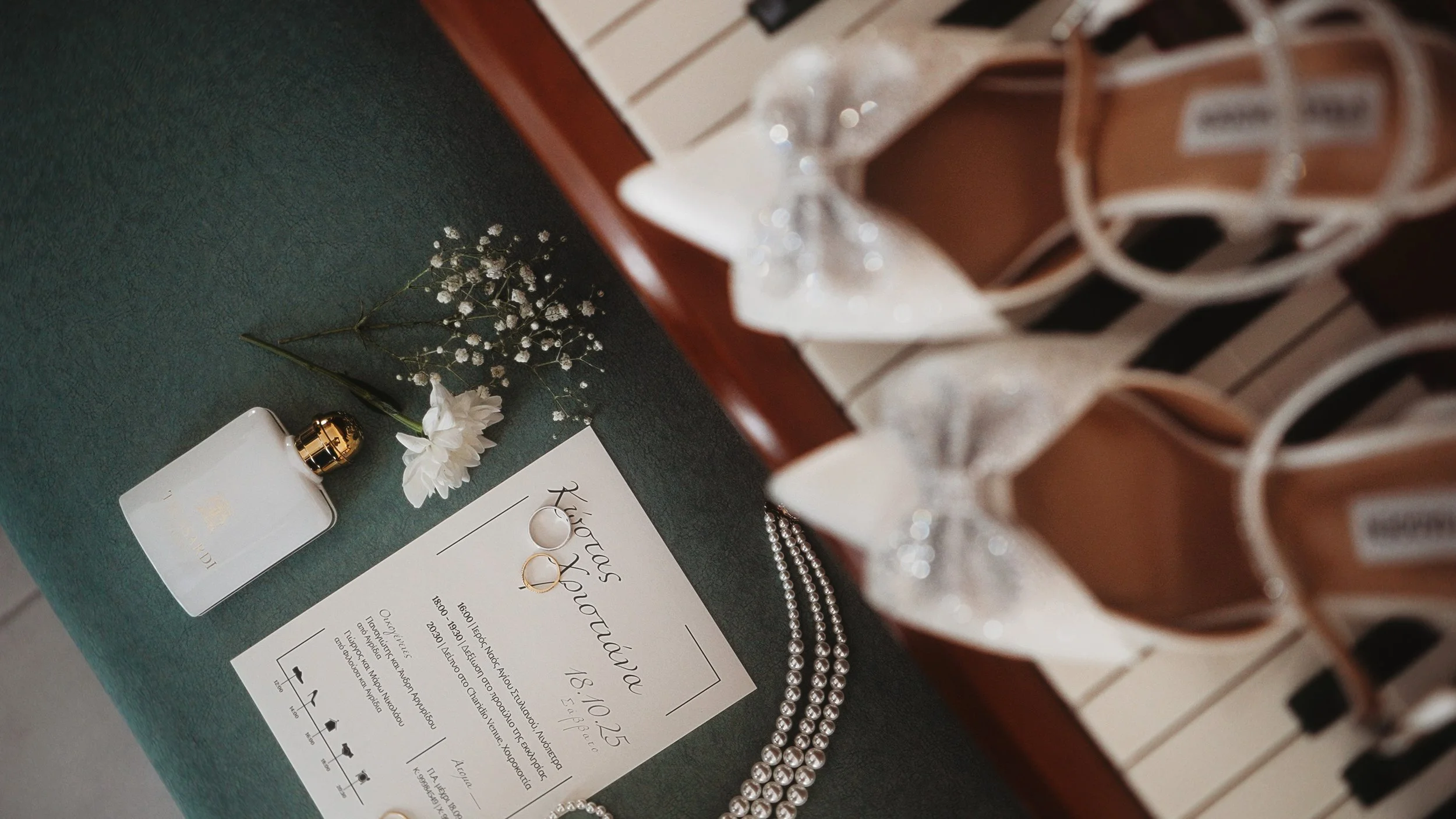 Wedding details flat lay on piano with invitation, rings, perfume, pearl necklace and bridal shoes, Kostas and Christiana wedding Cyprus, Red Lens Films