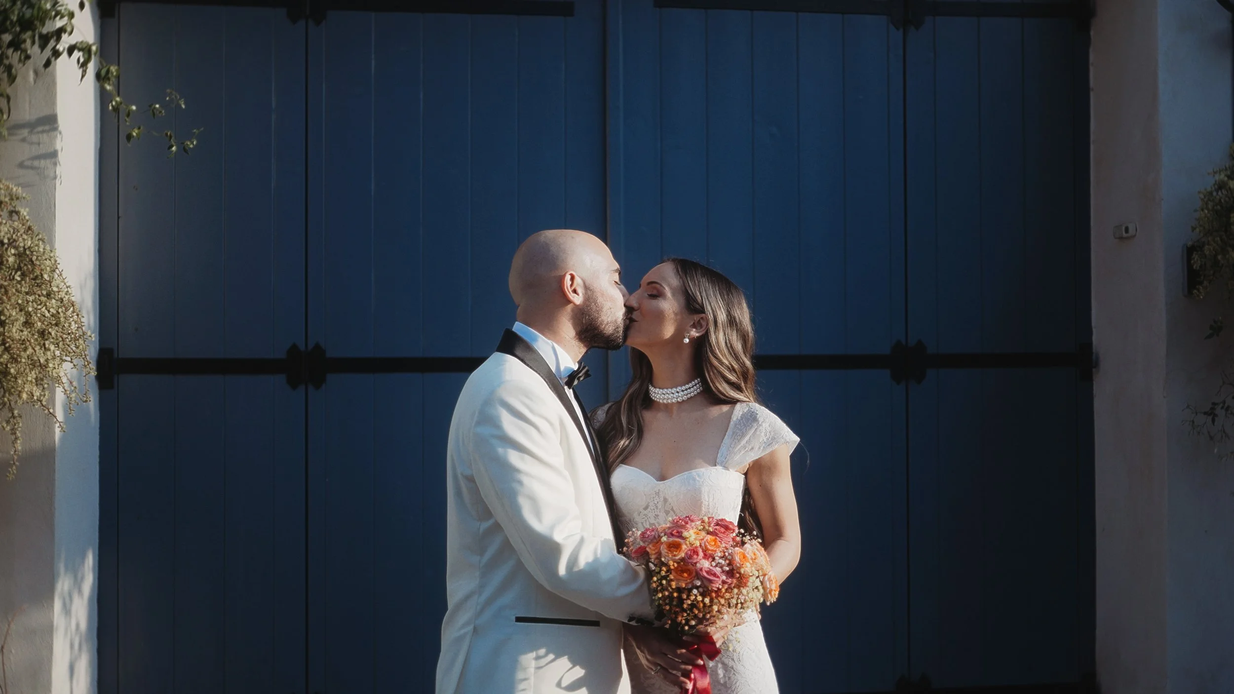 Couple kissing in front of blue wooden doors with bouquet, old town Limassol Cyprus, Red Lens Films