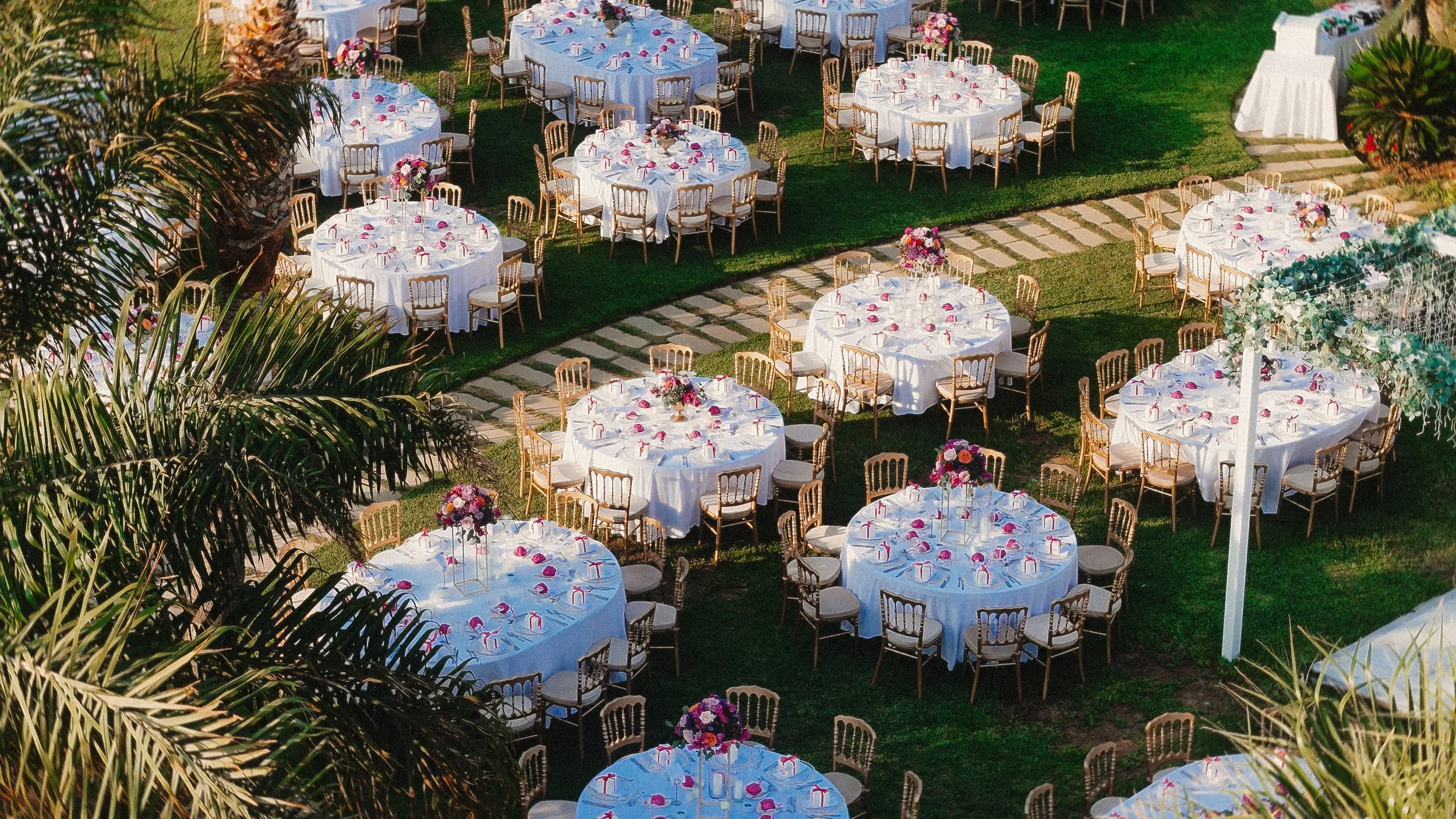 Outdoor wedding dinner setup at Amathus Beach Hotel with round tables arranged in the garden for Constantinos and Christina’s celebration