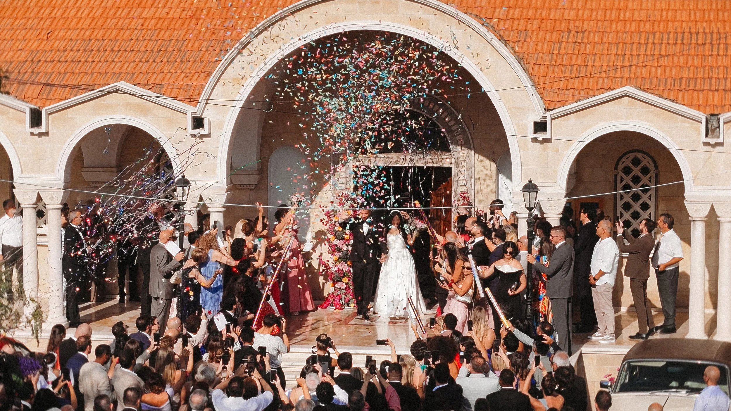 Constantinos and Christina walking out of the church as guests throw confetti after their Limassol wedding ceremony