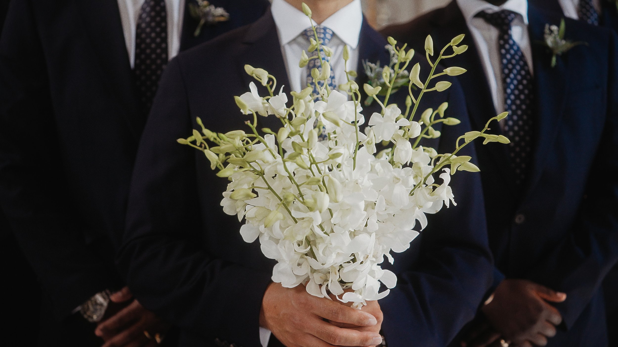 Groom holding white orchid bouquet with groomsmen before ceremony, Nicosia Cyprus, Red Lens Films