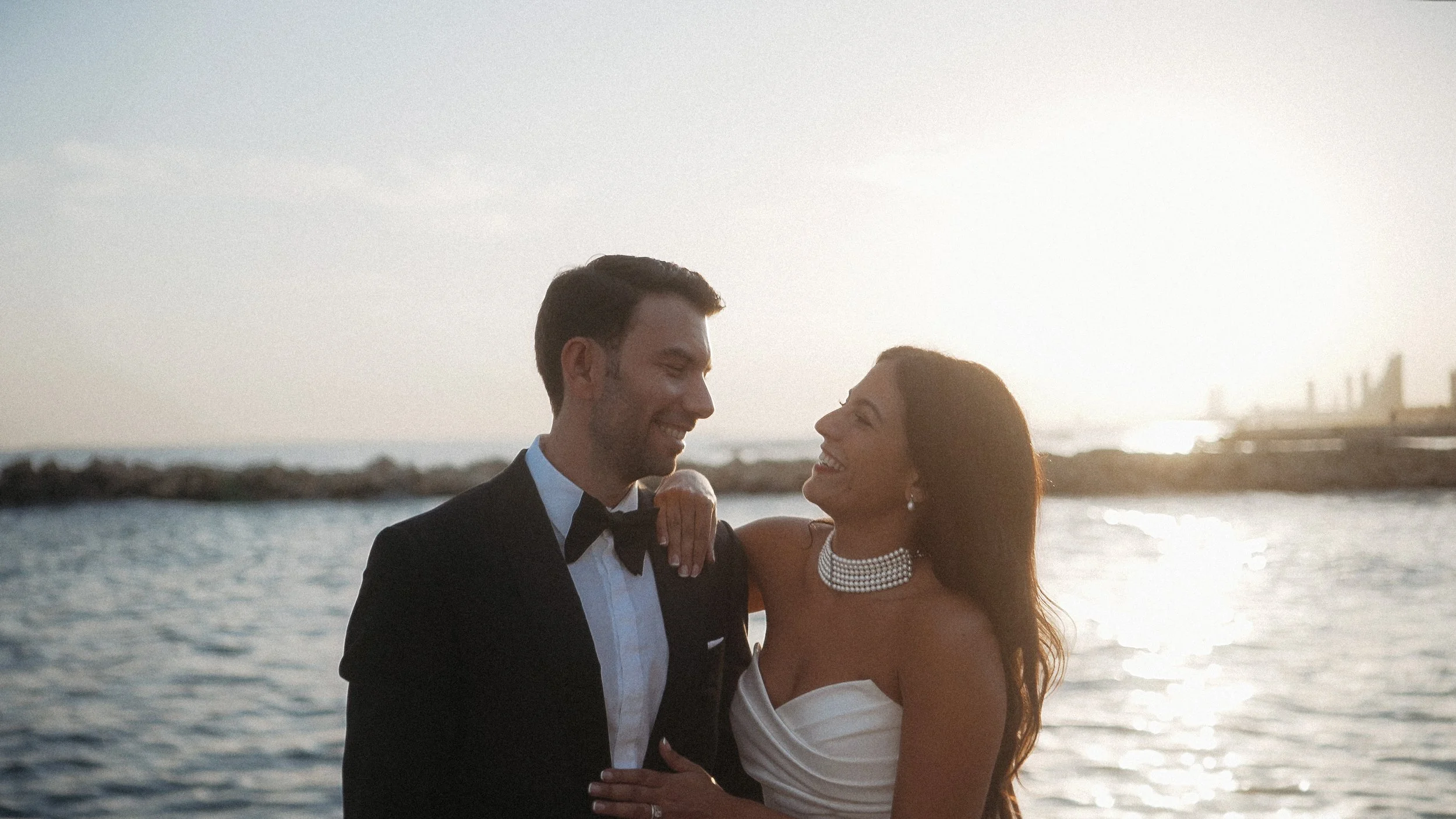 Constantinos and Christina laughing together during their wedding photoshoot at the pier of Amathus Beach Hotel at sunset