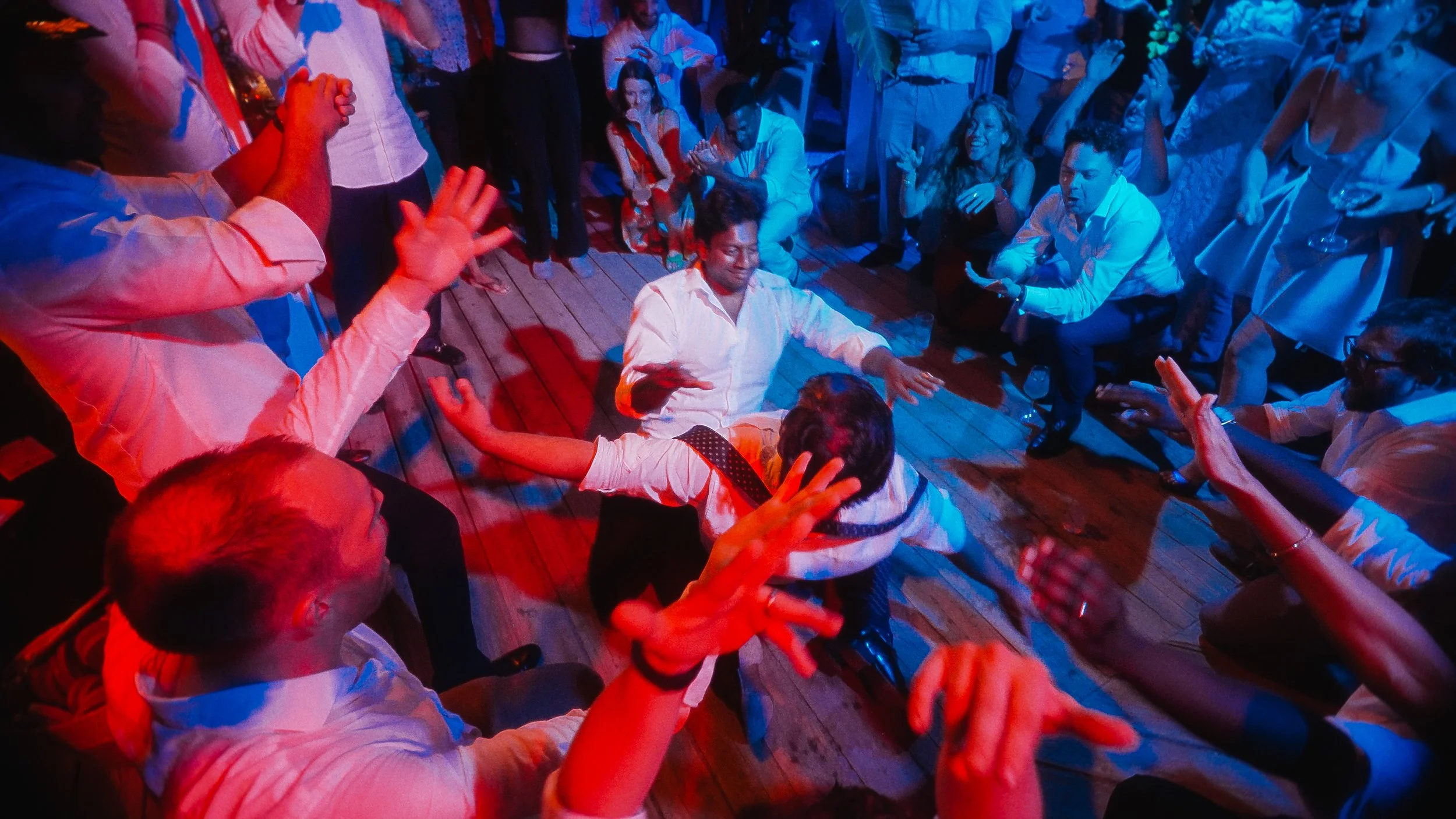 Guests cheering during zeimbekiko on the dancefloor, wedding reception Lady's Mile Beach Limassol Cyprus, Red Lens Films