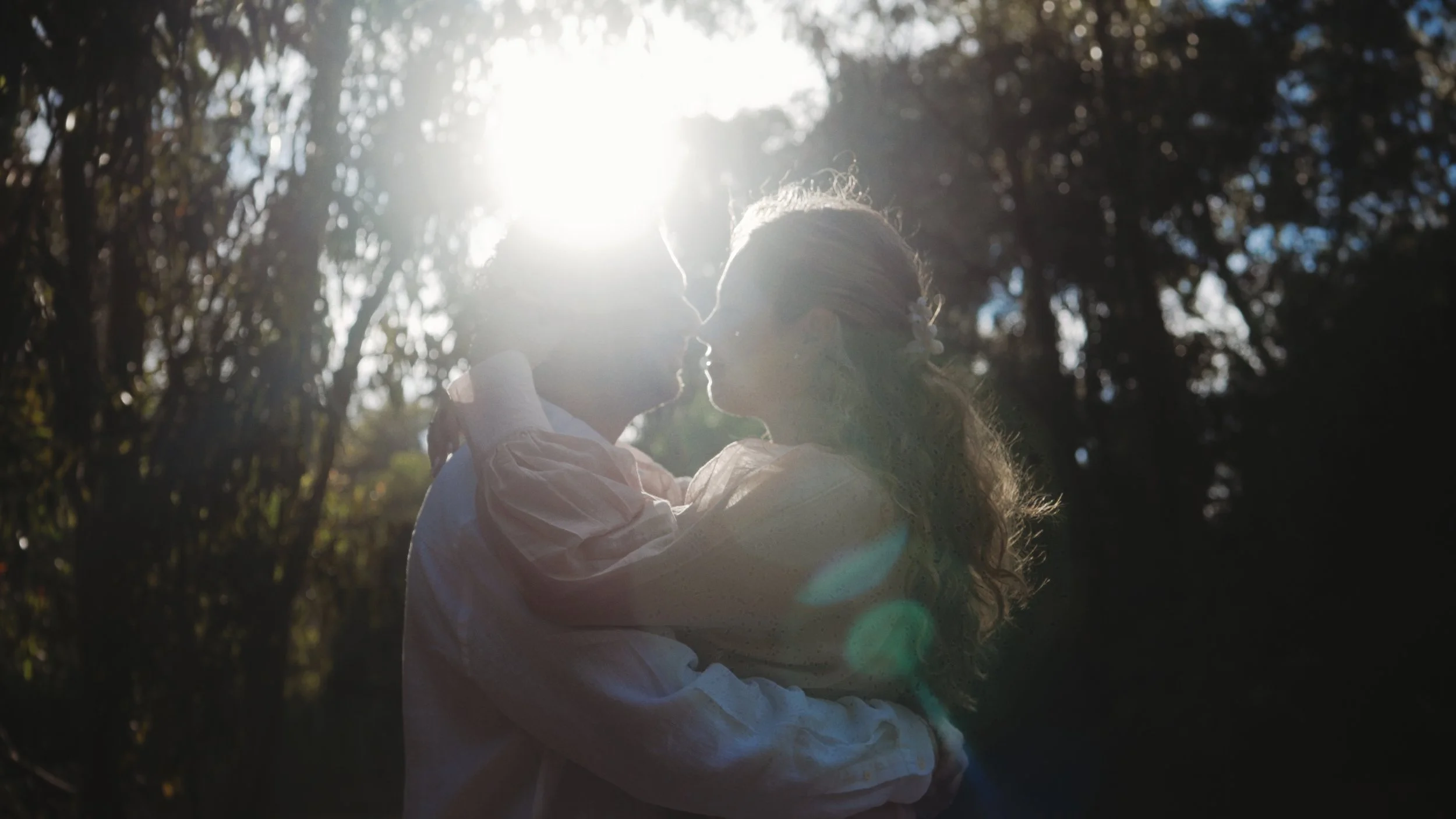 Couple kissing in backlit sun flare among the trees of the Akrotiri forest, Cyprus, Red Lens Films