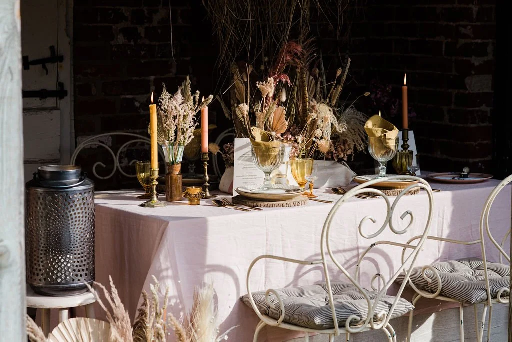 Pink, orange and gold styled dining table set within a brick walled barn