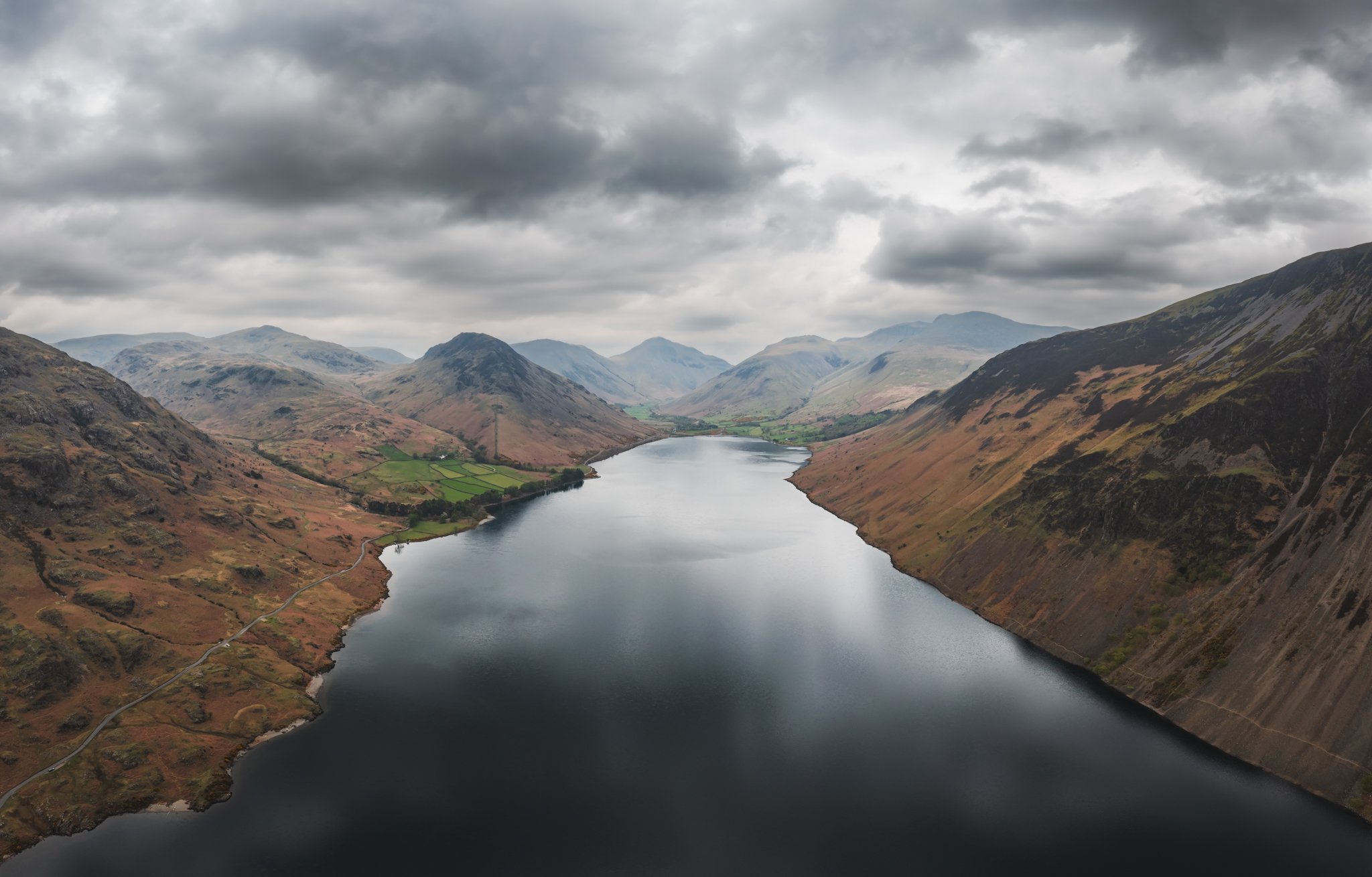A view of a river flowing between mountain valleys with cloudy skies above.