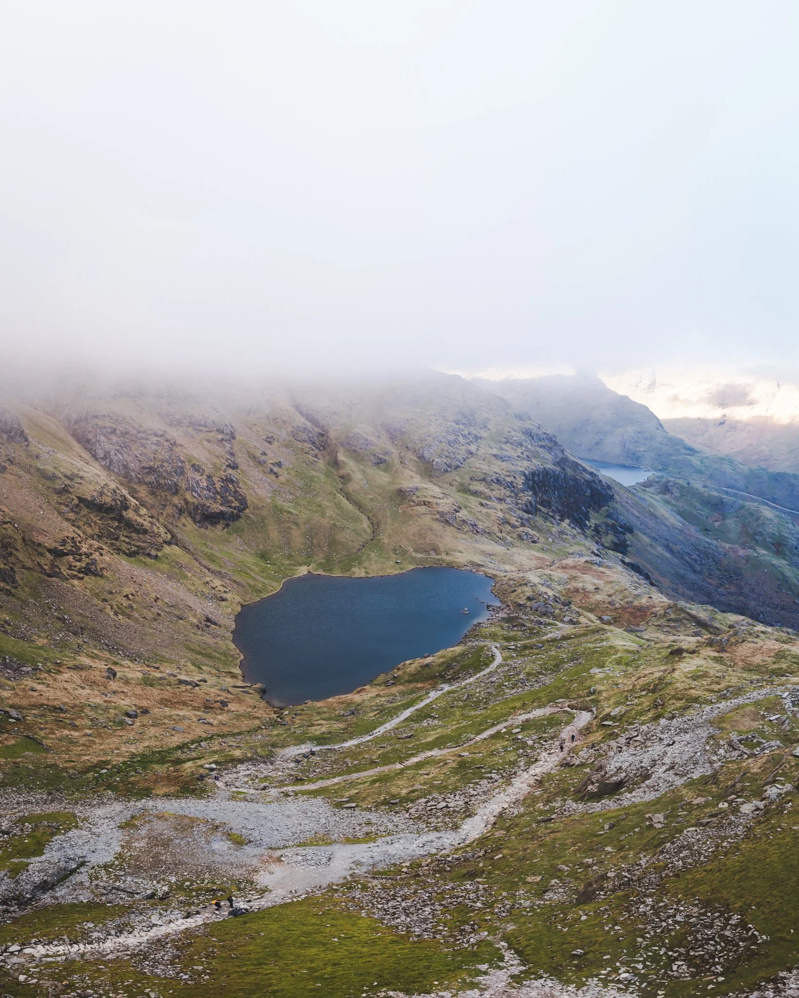 Mountain landscape with lakes and rocky terrain, partially covered by clouds.