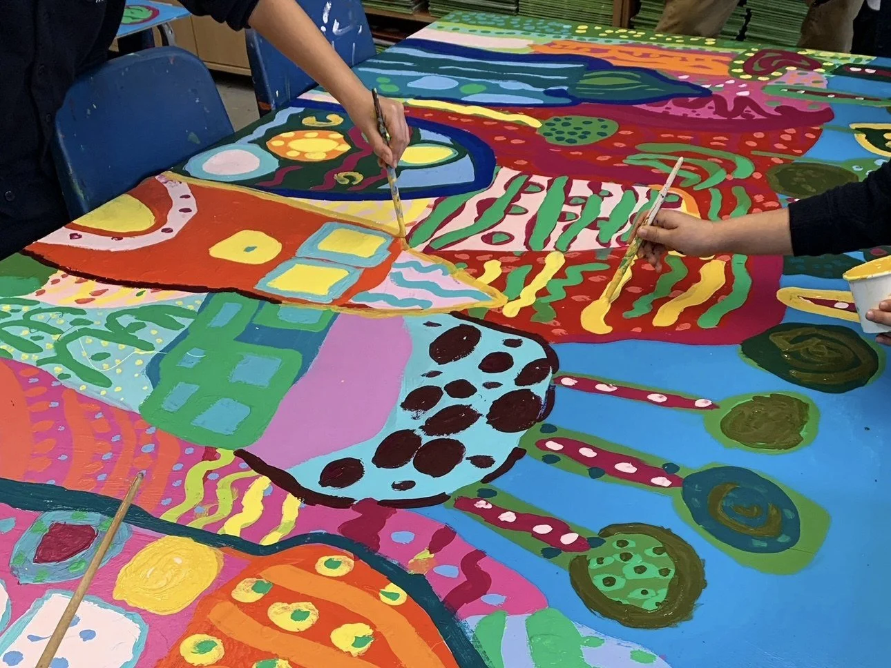 Children painting a large shared artwork in a classroom