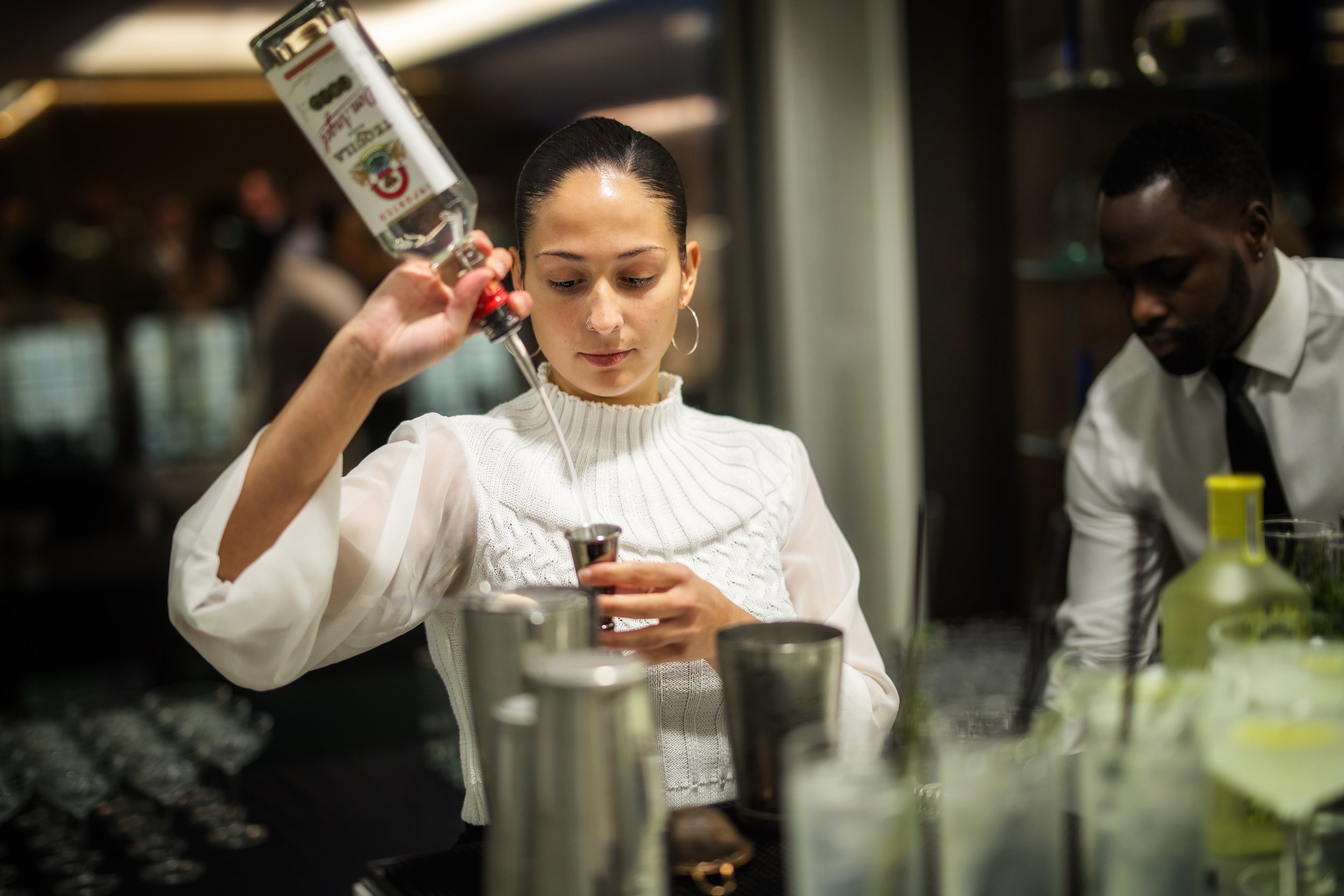 Private mixologist performing show-style cocktail technique at NYE house party.